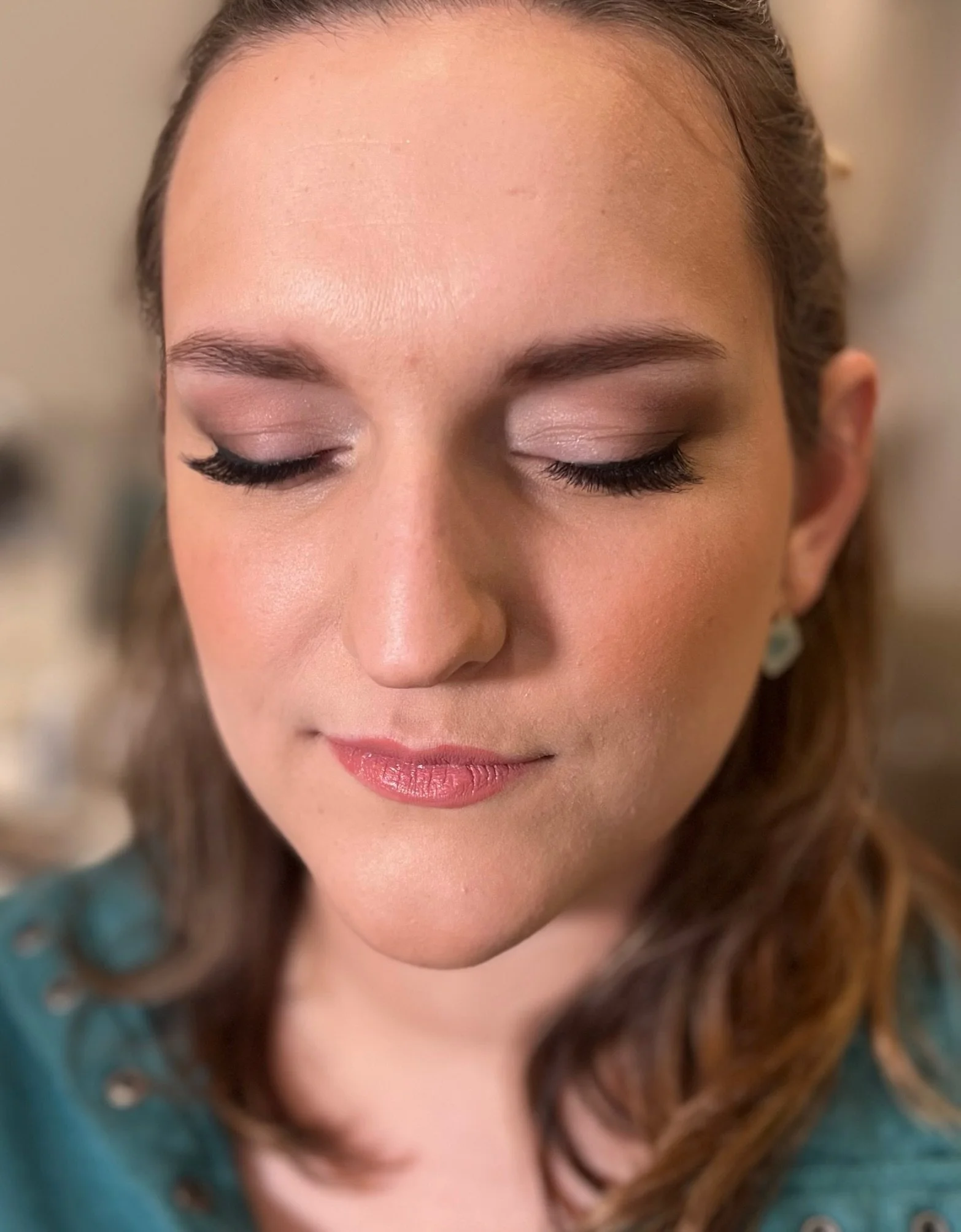 Close-up of a woman's face with closed eyes, wearing makeup, and brown hair.