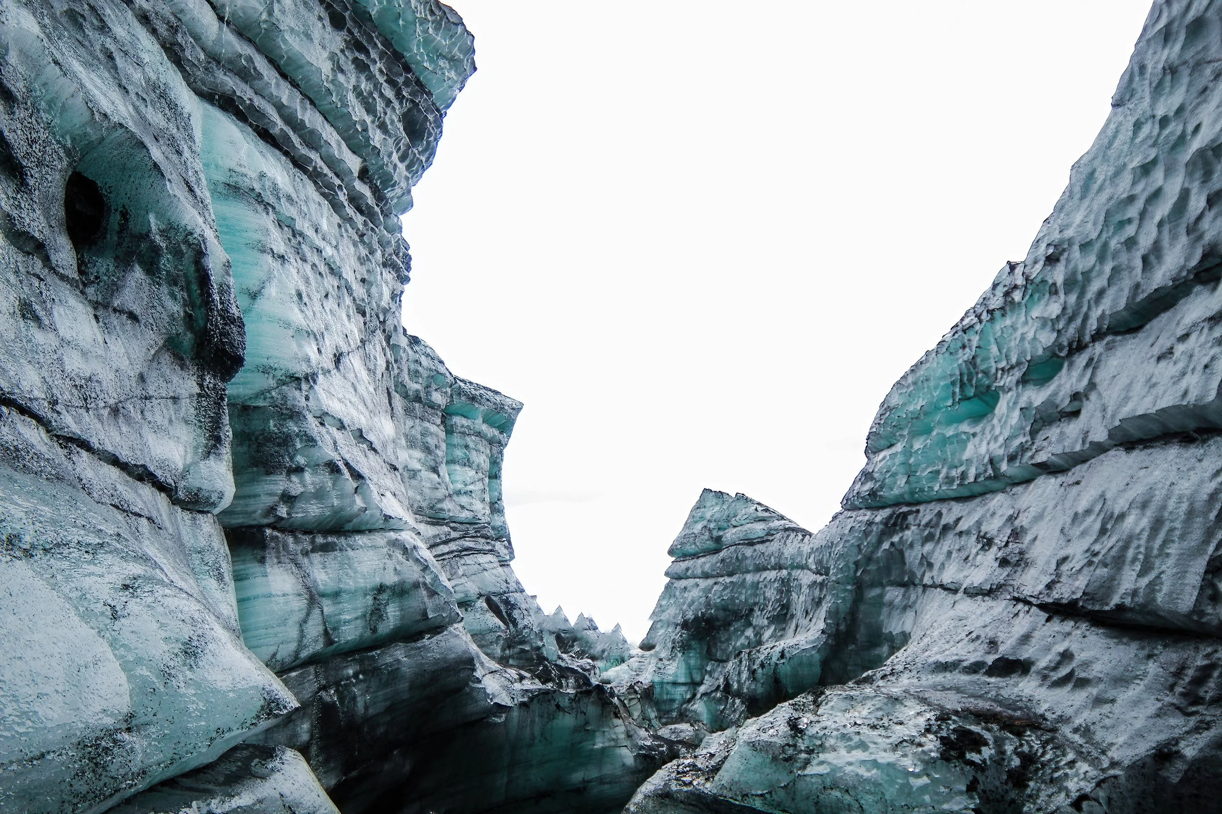 A glacier with jagged ice formations and crevasses, viewed from within a narrow ice canyon.