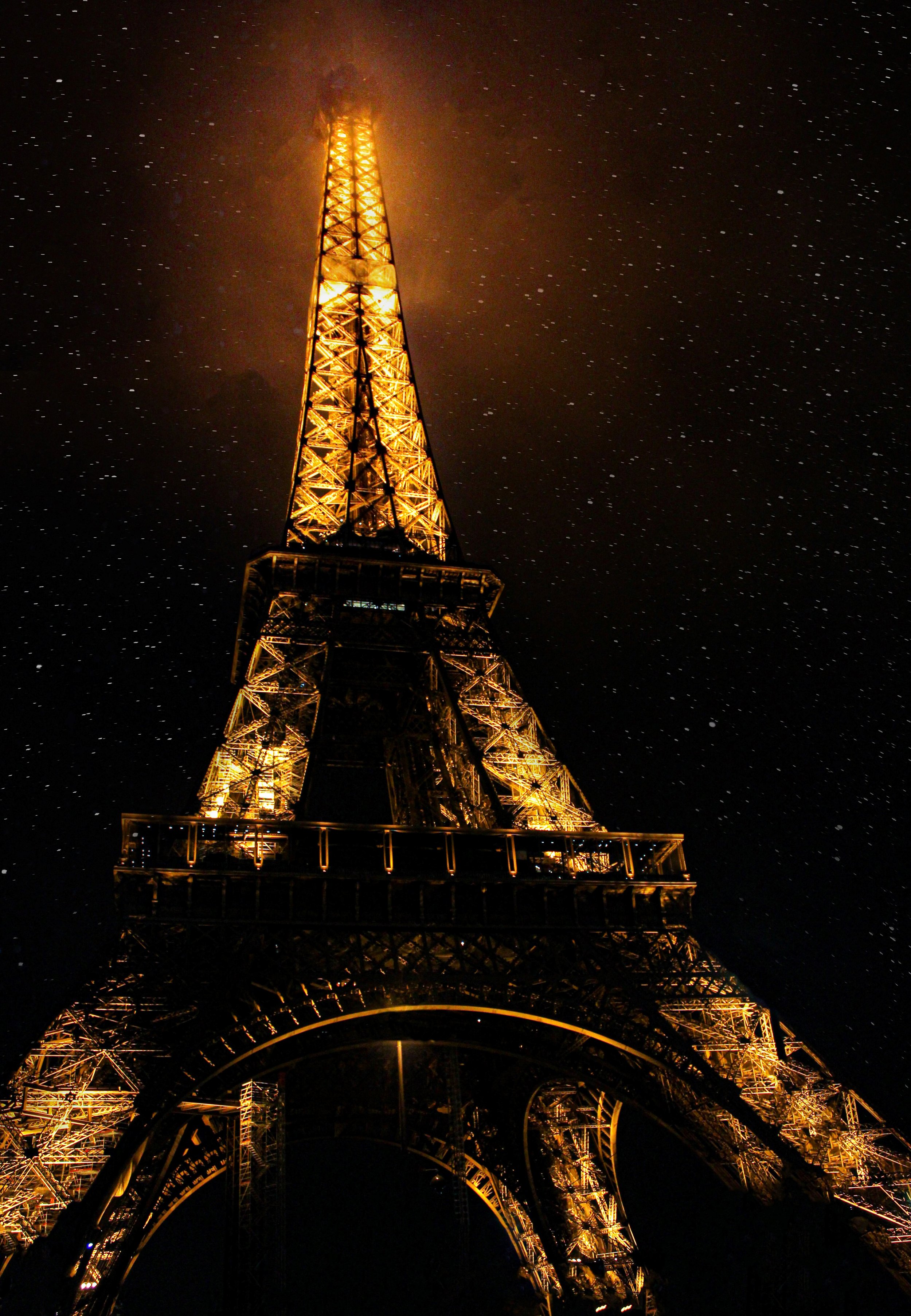Nighttime view of the Eiffel Tower illuminated with golden lights against a starry sky.