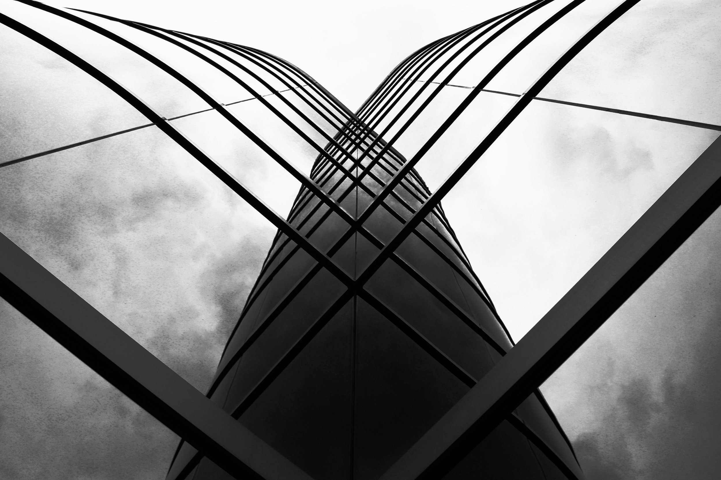 Black and white photo of a modern glass and steel skyscraper, taken from below looking up.