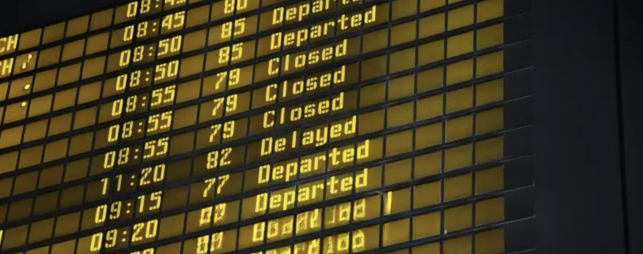 Airport departure and arrival display board showing times and statuses of flights, such as departed, delayed, and closed.