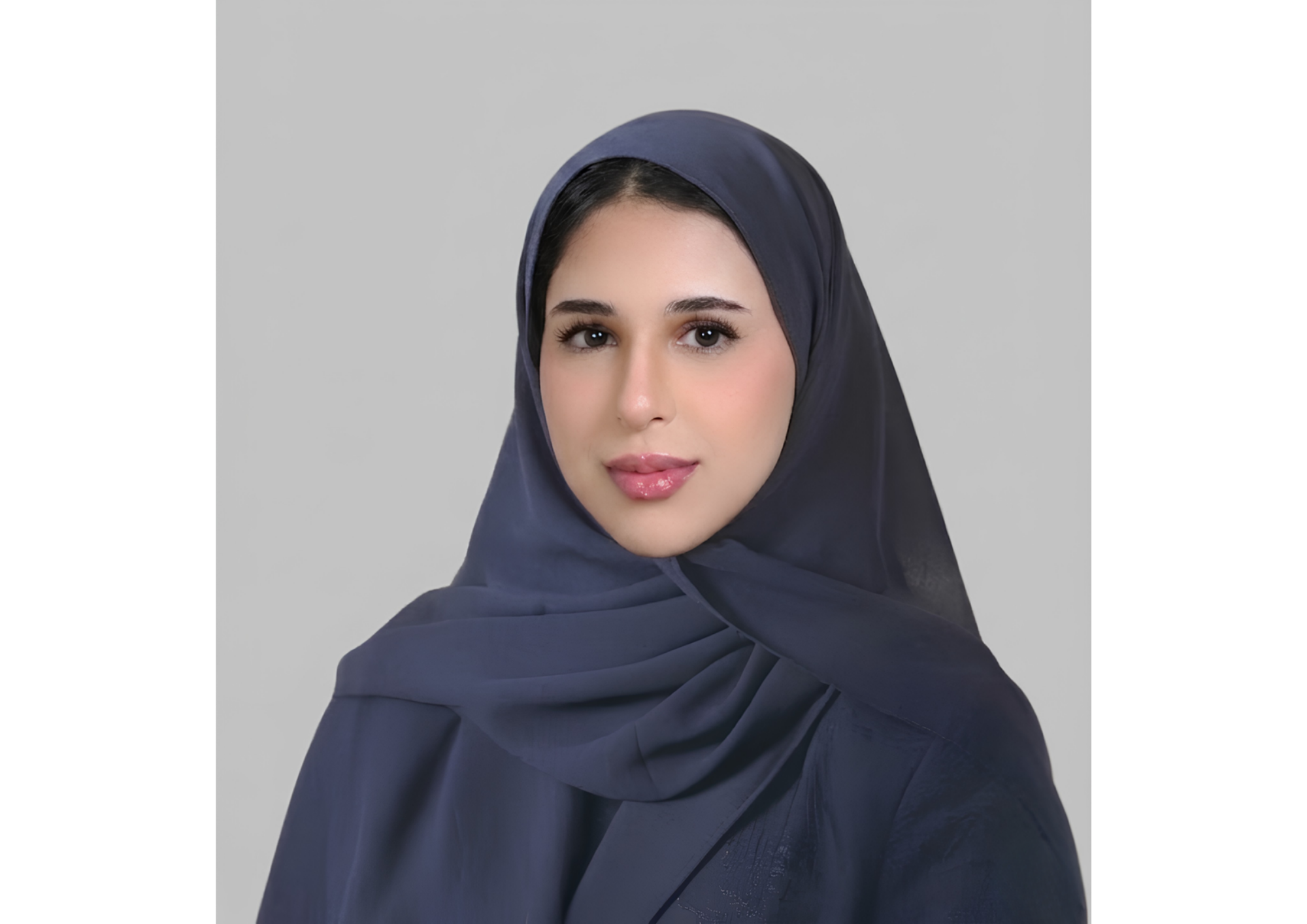 A woman wearing a navy blue hijab looking at the camera with a neutral expression.