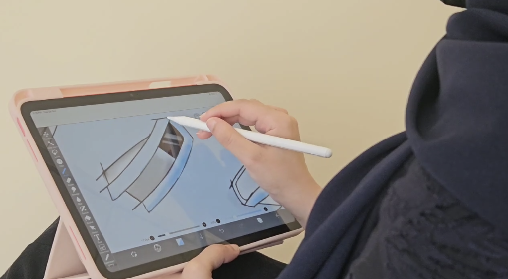 Person drawing a 3D model of a chair on a tablet with a stylus.