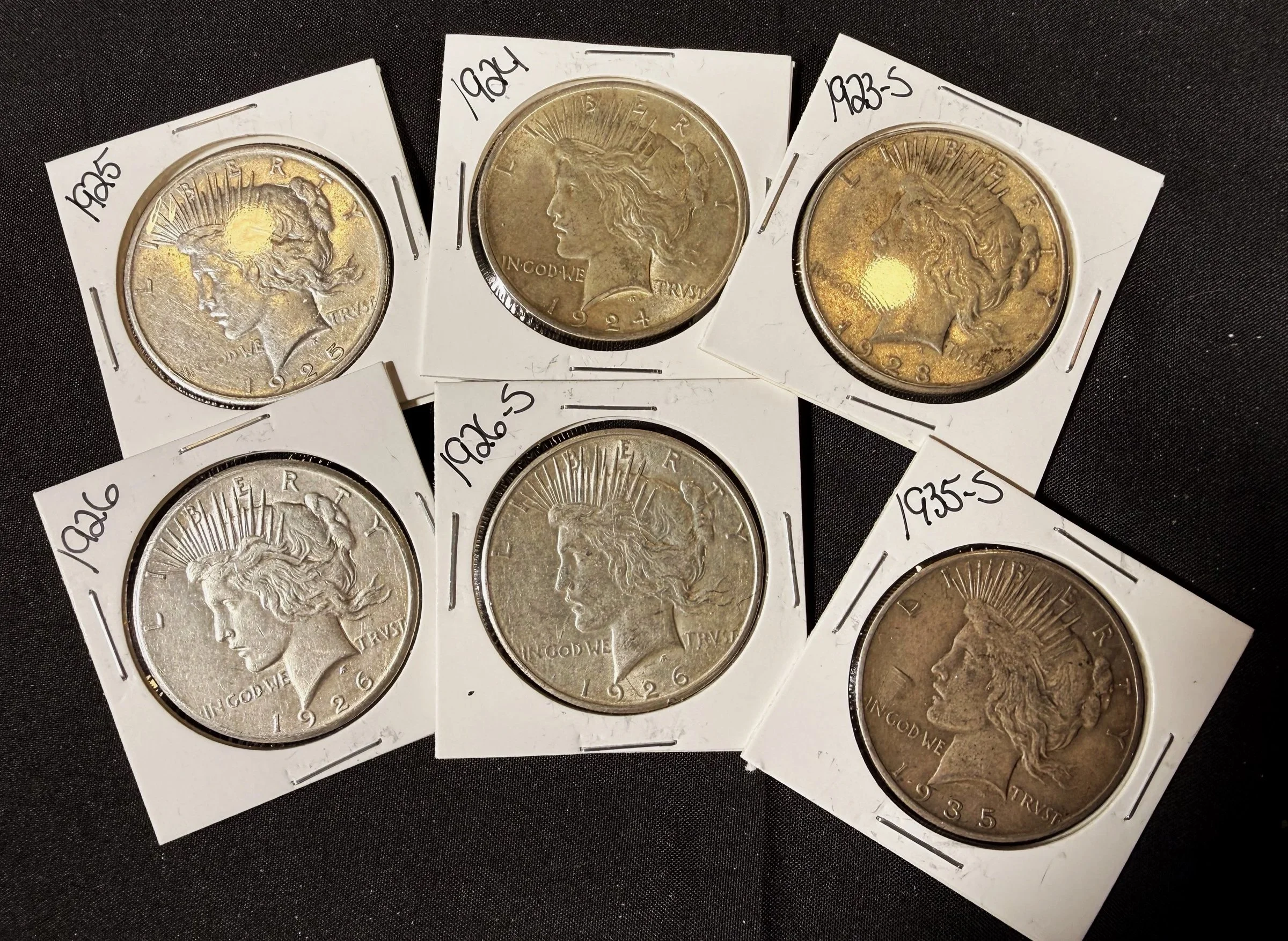 Collection of vintage American quarters from different years, each in protective cardboard holder with handwritten labels showing the year, including 1925, 1924, 1933-S, 1926, and 1935-S.