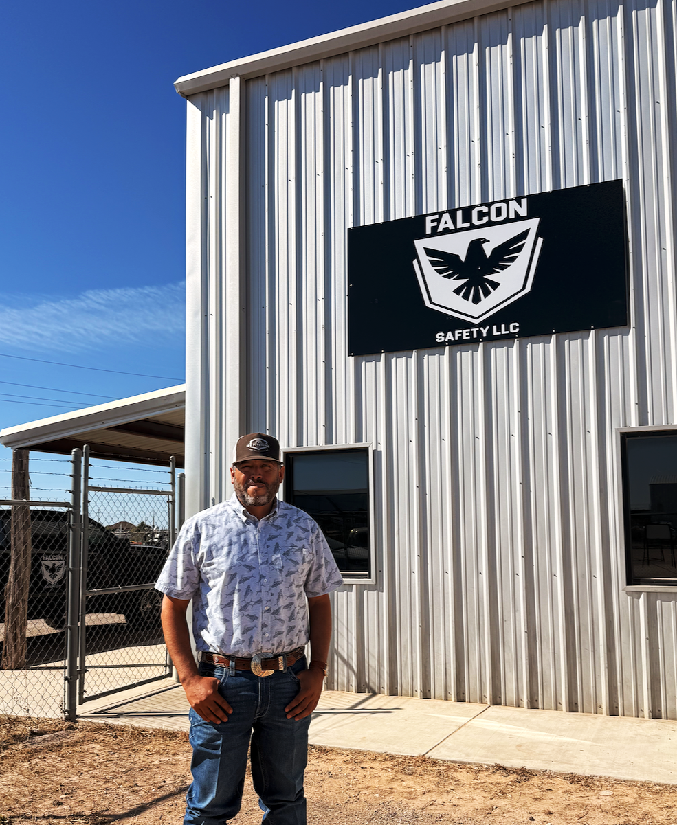 Man standing outside Falcon Safety LLC building with metal siding and logo sign