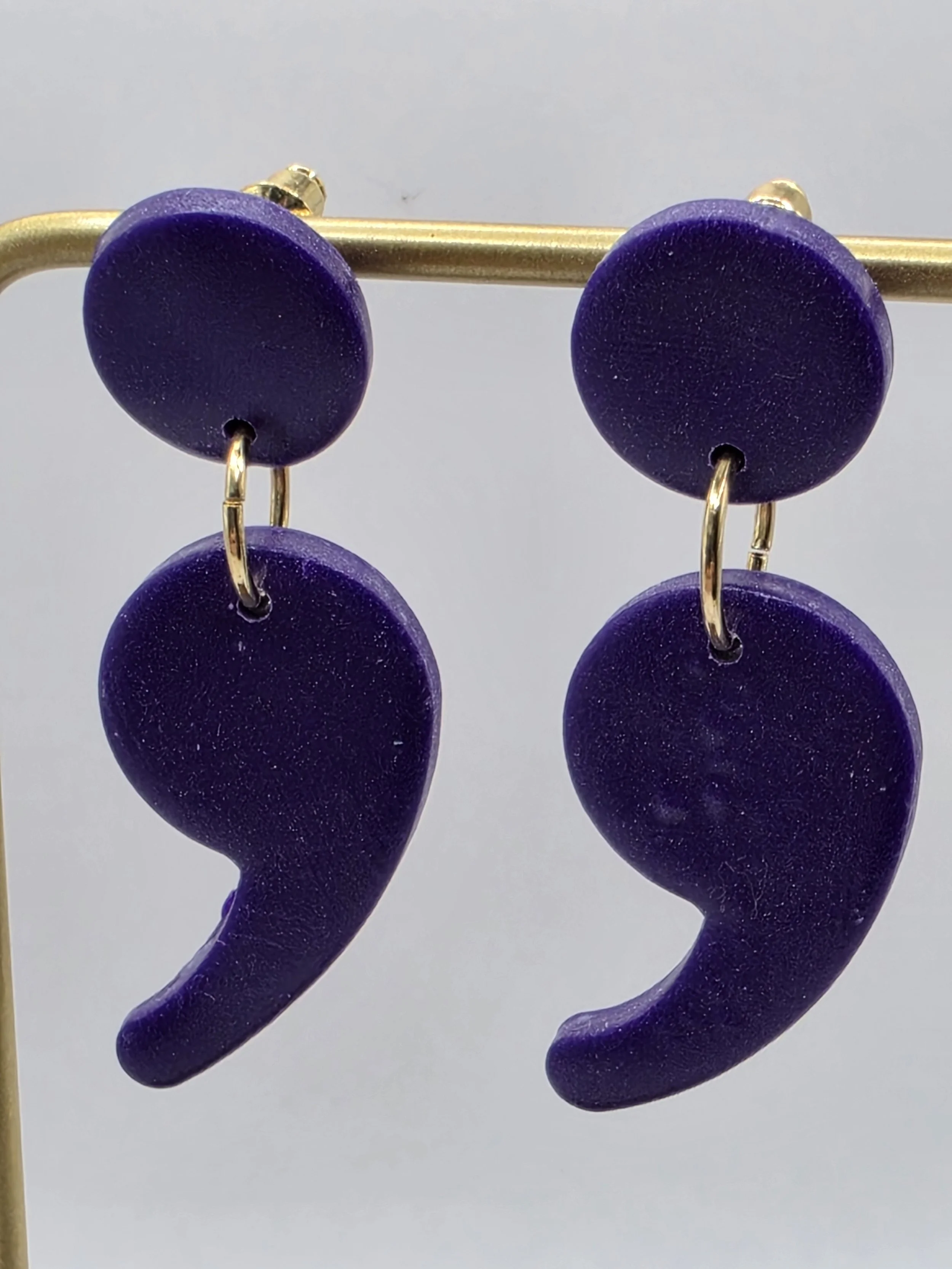 Purple earrings with spiral-shaped dangles on a white background.