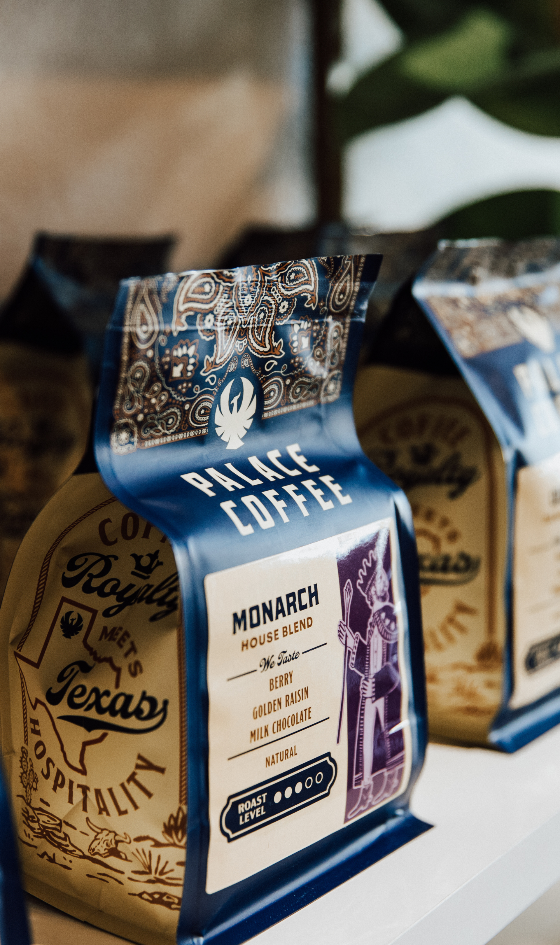 Close-up of a bag of Palace Coffee Monarch House Blend, featuring a detailed label with flavor notes such as berry, golden raisin, milk chocolate, and natural, with a roast level indicator.