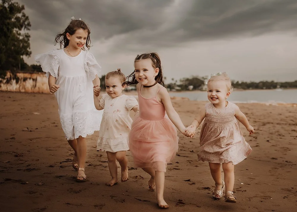 A group of young children running along the beach in Darwin with a stormy sky in the background. By Captured by Cody.