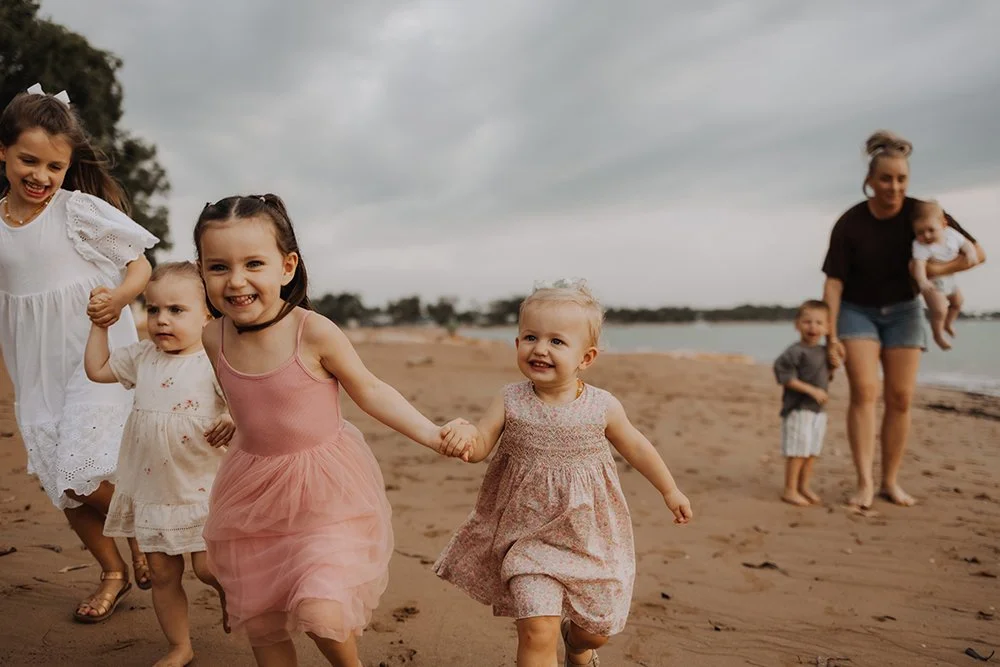 A group of young cousins running on the beach. Family photography by Captured by Cody.