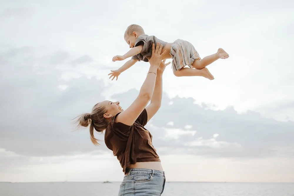 A woman lifts her young son high into the air. by Captured by Cody, Darwin, NT