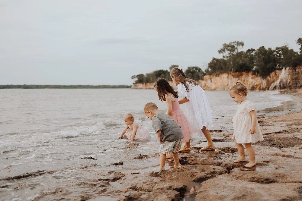 A group of children standing on the rocky shoreline in Darwin for a family photography shoot by Captured by Cody.