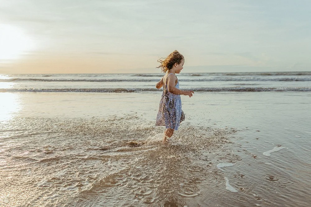 A young girl running on the beach on the NT coast. Family photography by Captured by Cody.