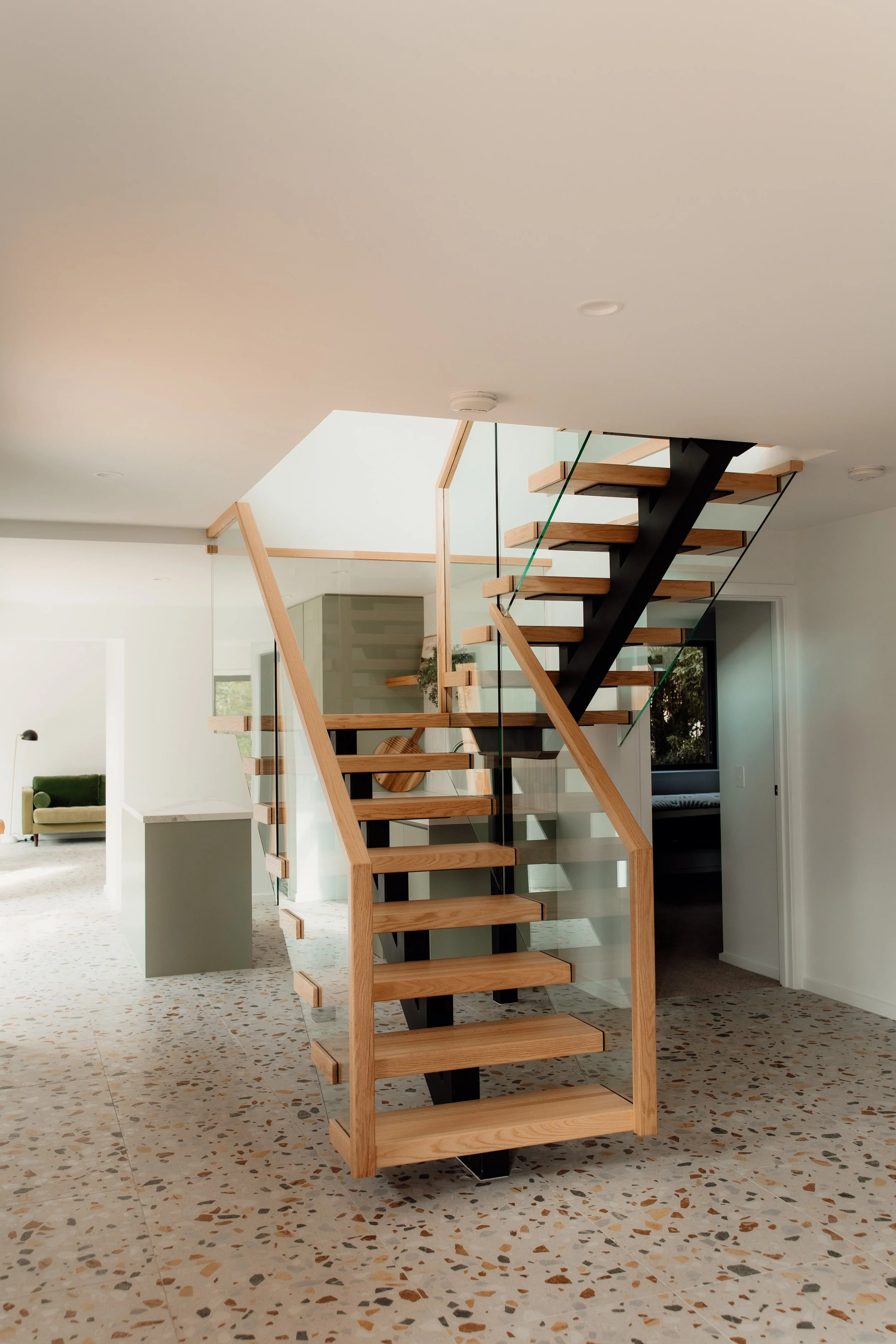 Modern indoor staircase with wooden steps and glass sides in a bright home.