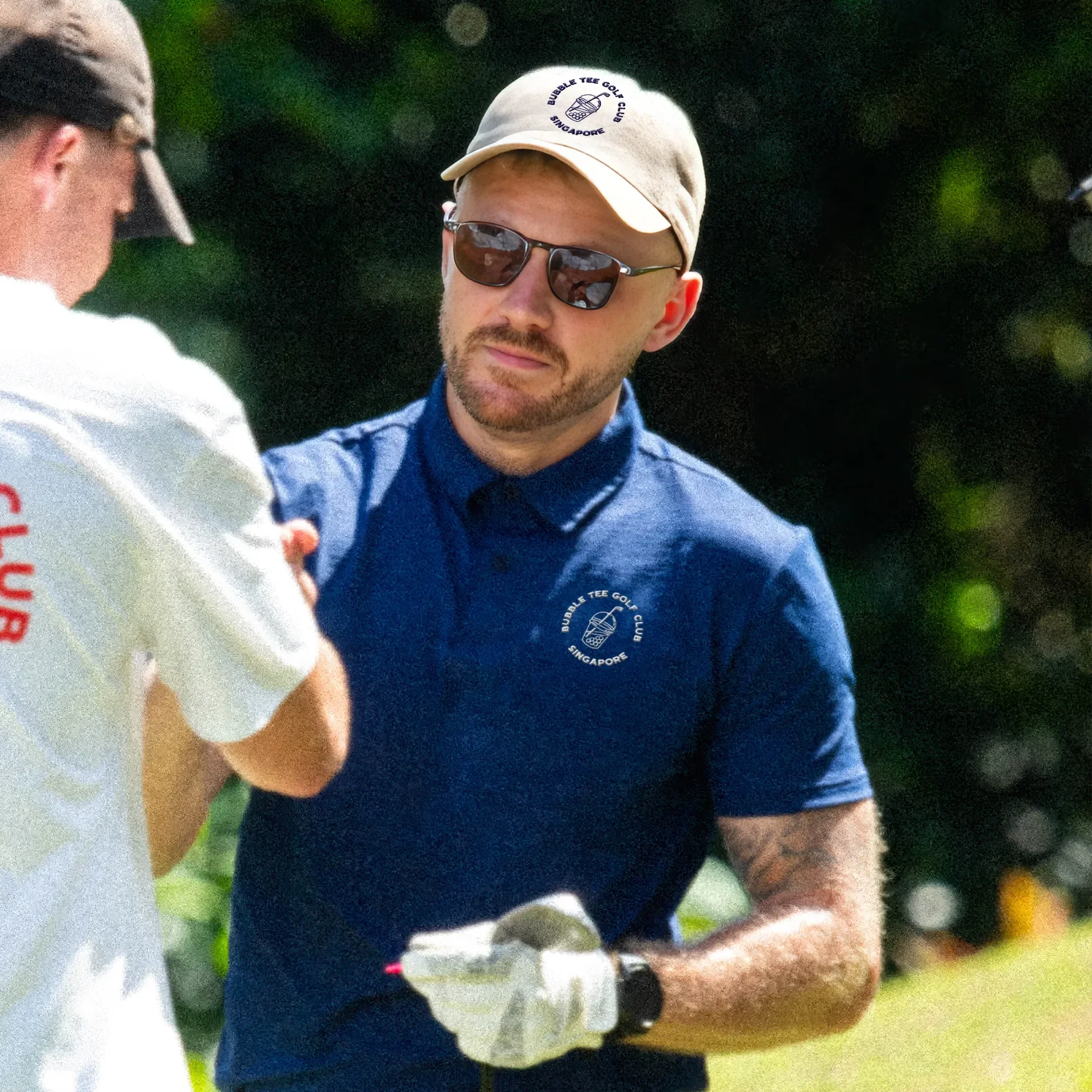 Golfer wearing a khaki Bubble Tee Golf Club Singapore cap with embroidered logo, paired with premium golf apparel on a tropical golf course.