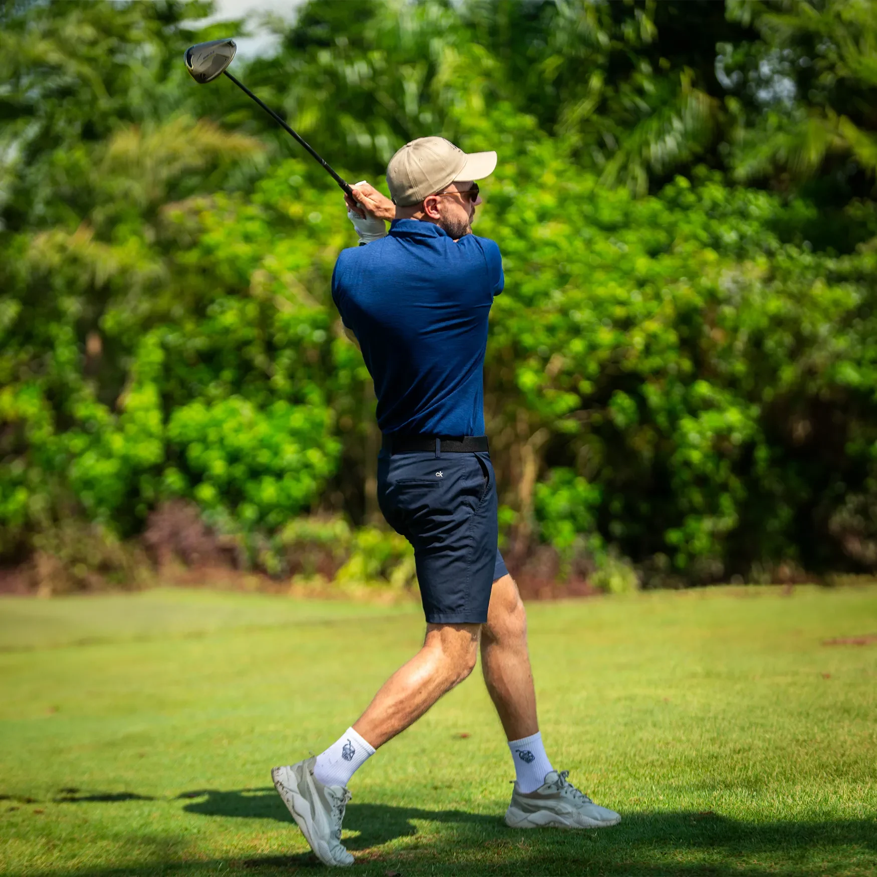 Male golfer playing on a golf course wearing a navy blue Bubble Tee Golf Club polo shirt with embroidered Singapore logo.