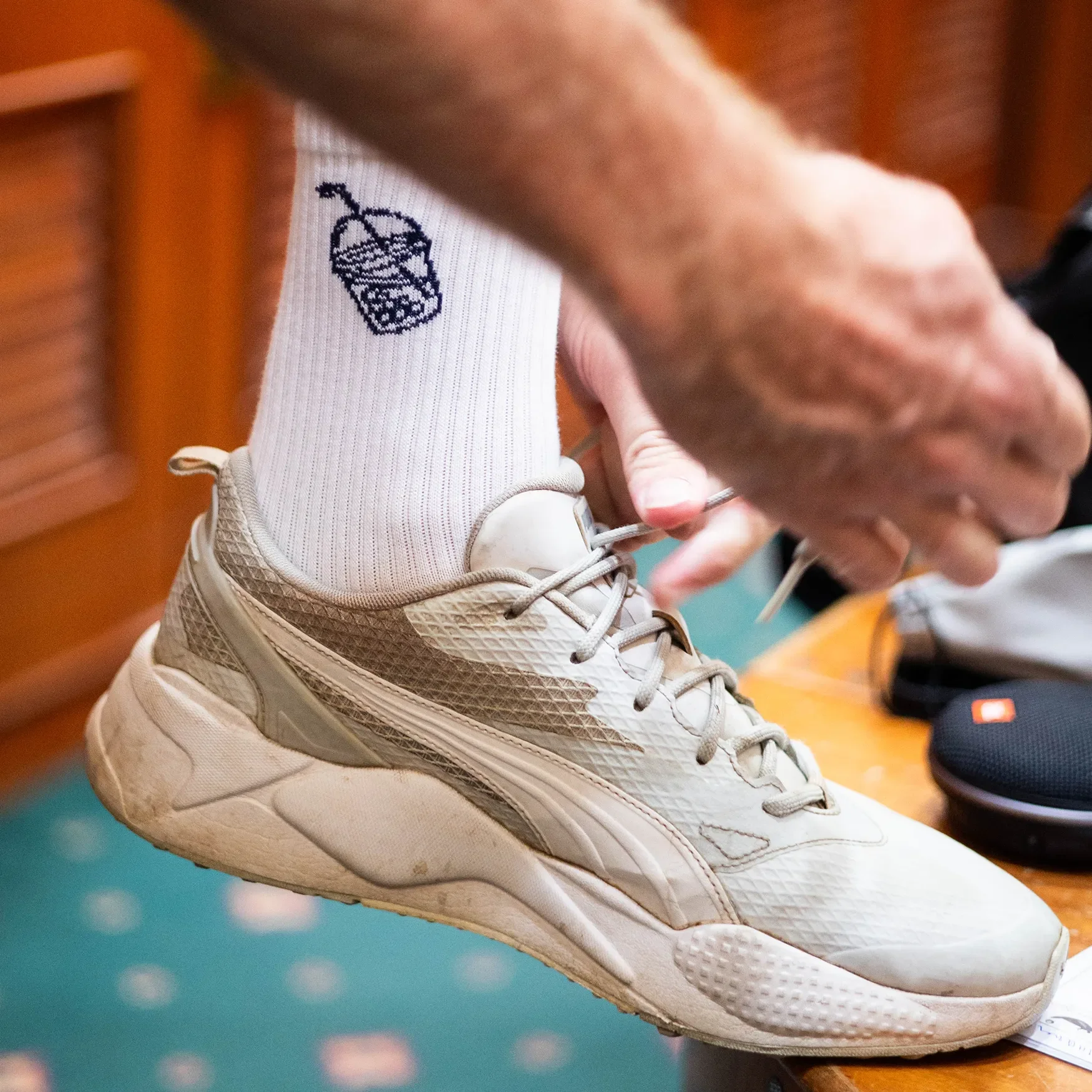 White Bubble Tee Golf Club crew socks with dark blue embroidered logo detail, styled with modern golf footwear in a premium clubhouse setting.