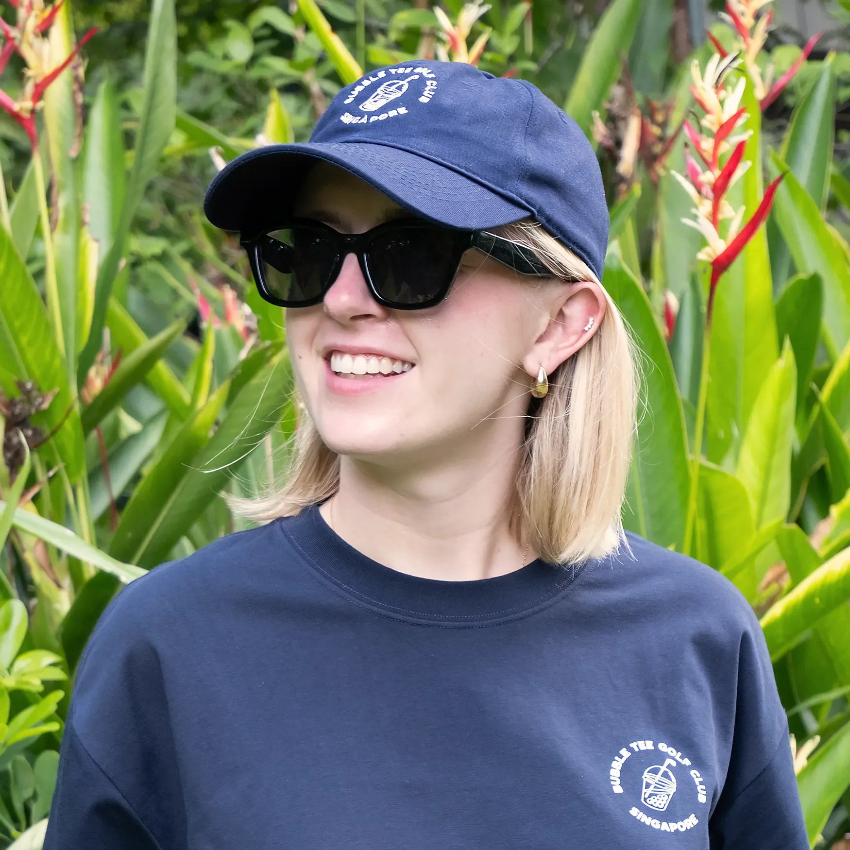 Close-up of female golfer wearing a navy blue Bubble Tee Golf Club Singapore cap with embroidered logo, styled for the golf course, modern streetwear-inspired golf apparel.