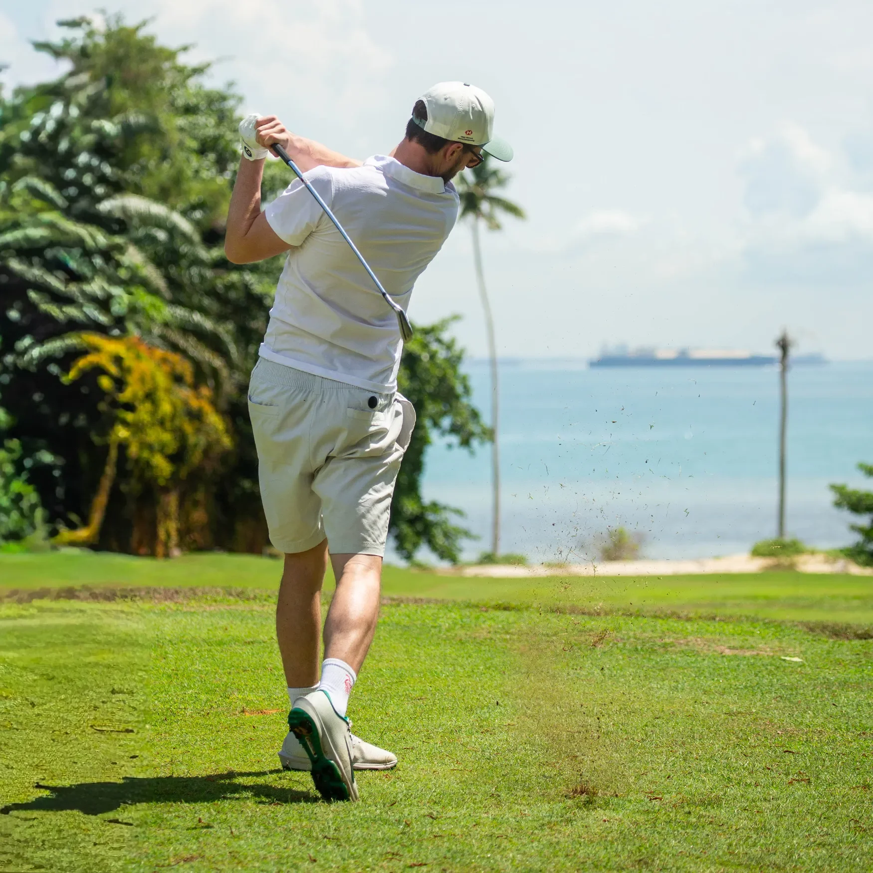 Male golfer wearing a white Bubble Tee Golf Club polo shirt, playing a shot on a Singapore golf course.