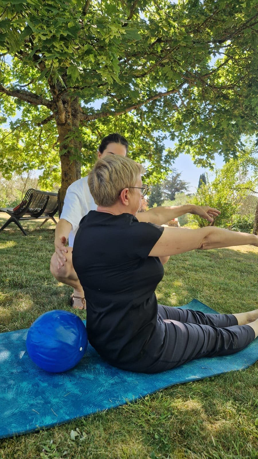 Coach sportive qui corrige une élève lors d'un cours de Pilates en plein air