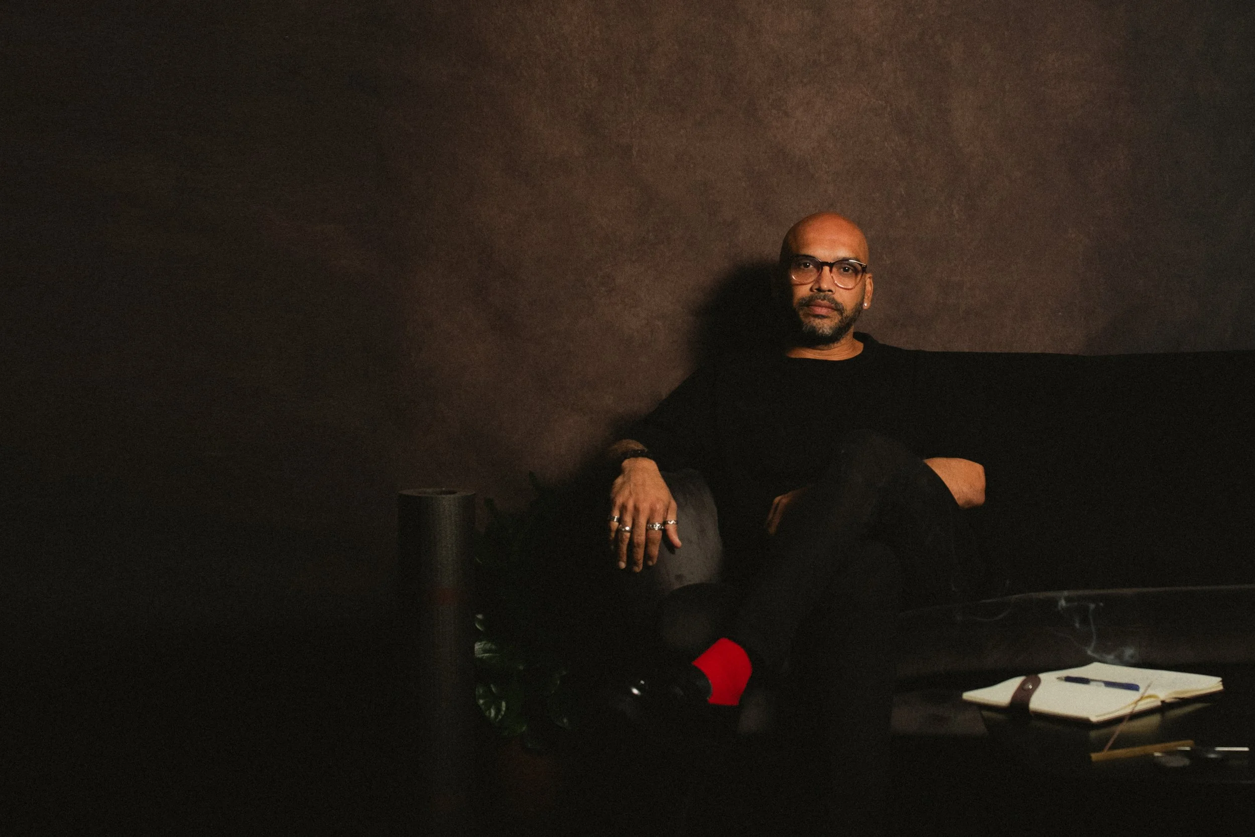 Ryan Chhajed, mindfulness and performance coach, seated in a dark interior setting.