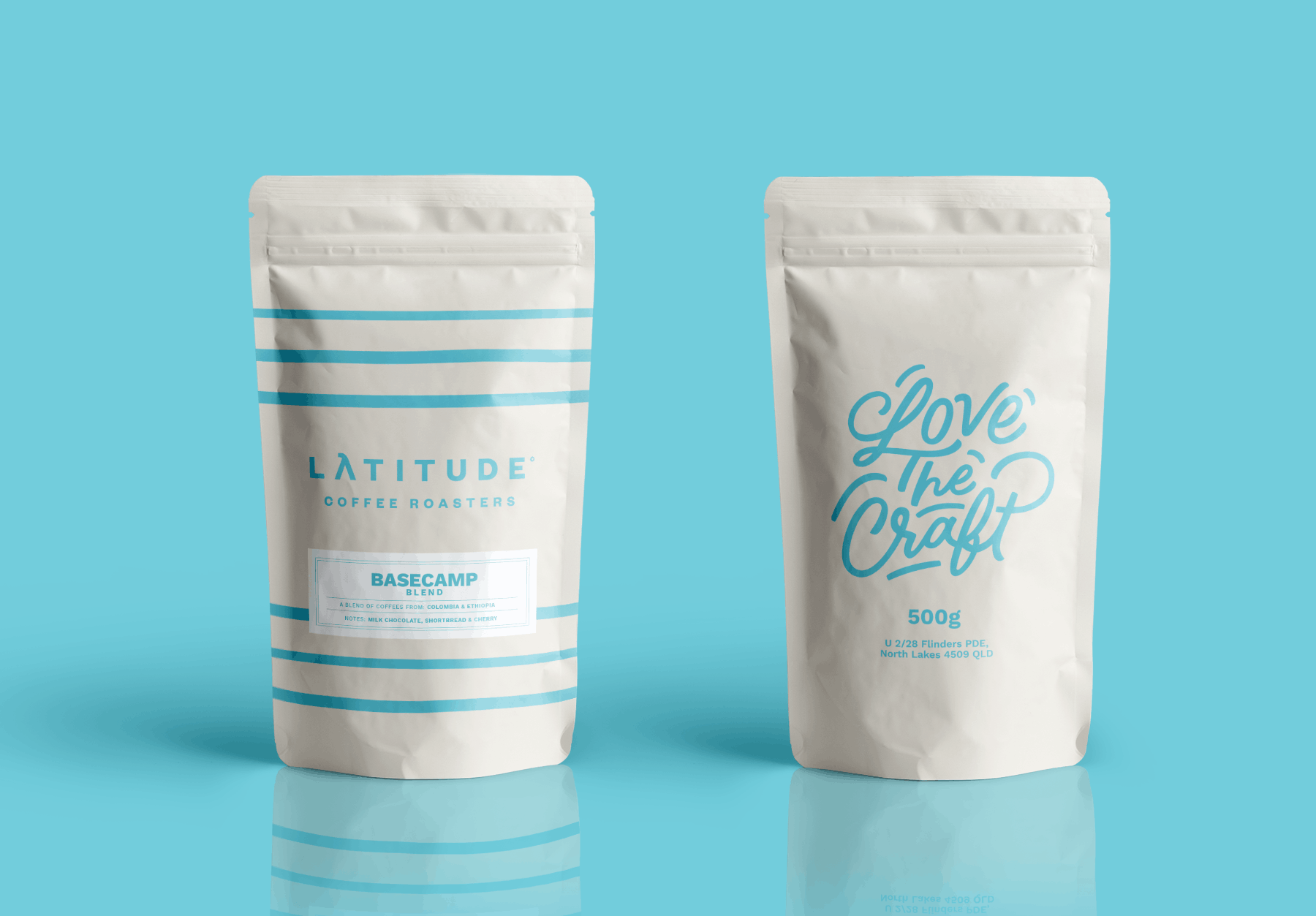 Two white Latitude Coffee coffee bags with blue text and designs, standing upright against a blue background, featuring brands 'Latitude Coffee Roasters' and 'Love The Craft'.