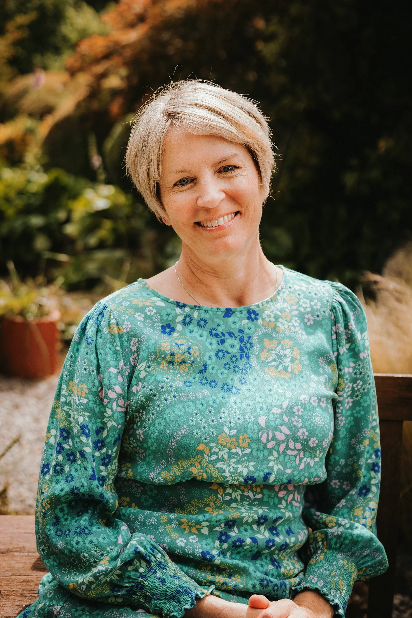 The company founder and director smiling warmly in a garden setting.