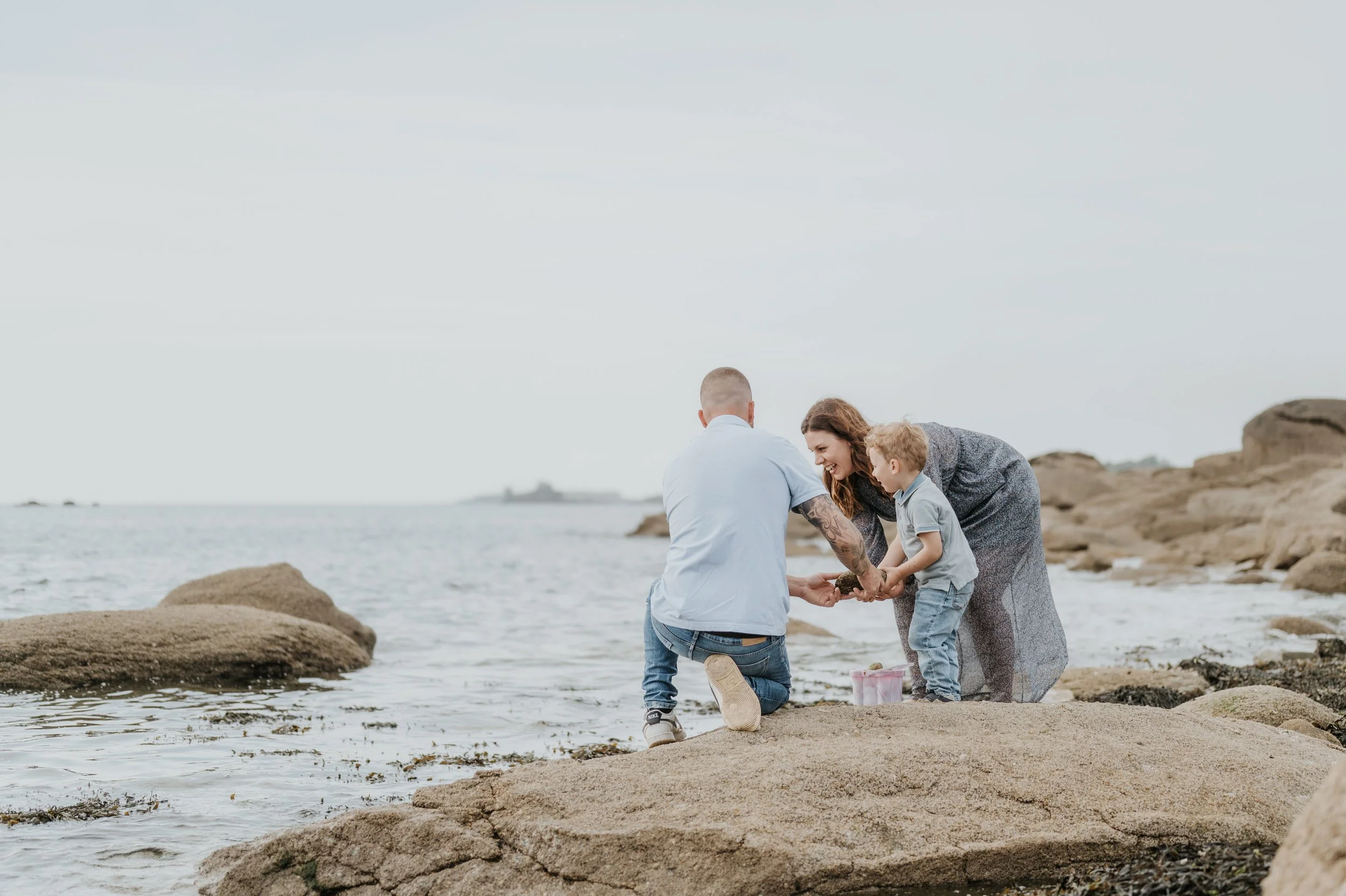 Une famille au bord de la mer, père, mère et enfant, partageant un moment joyeux en tenant une coquille.