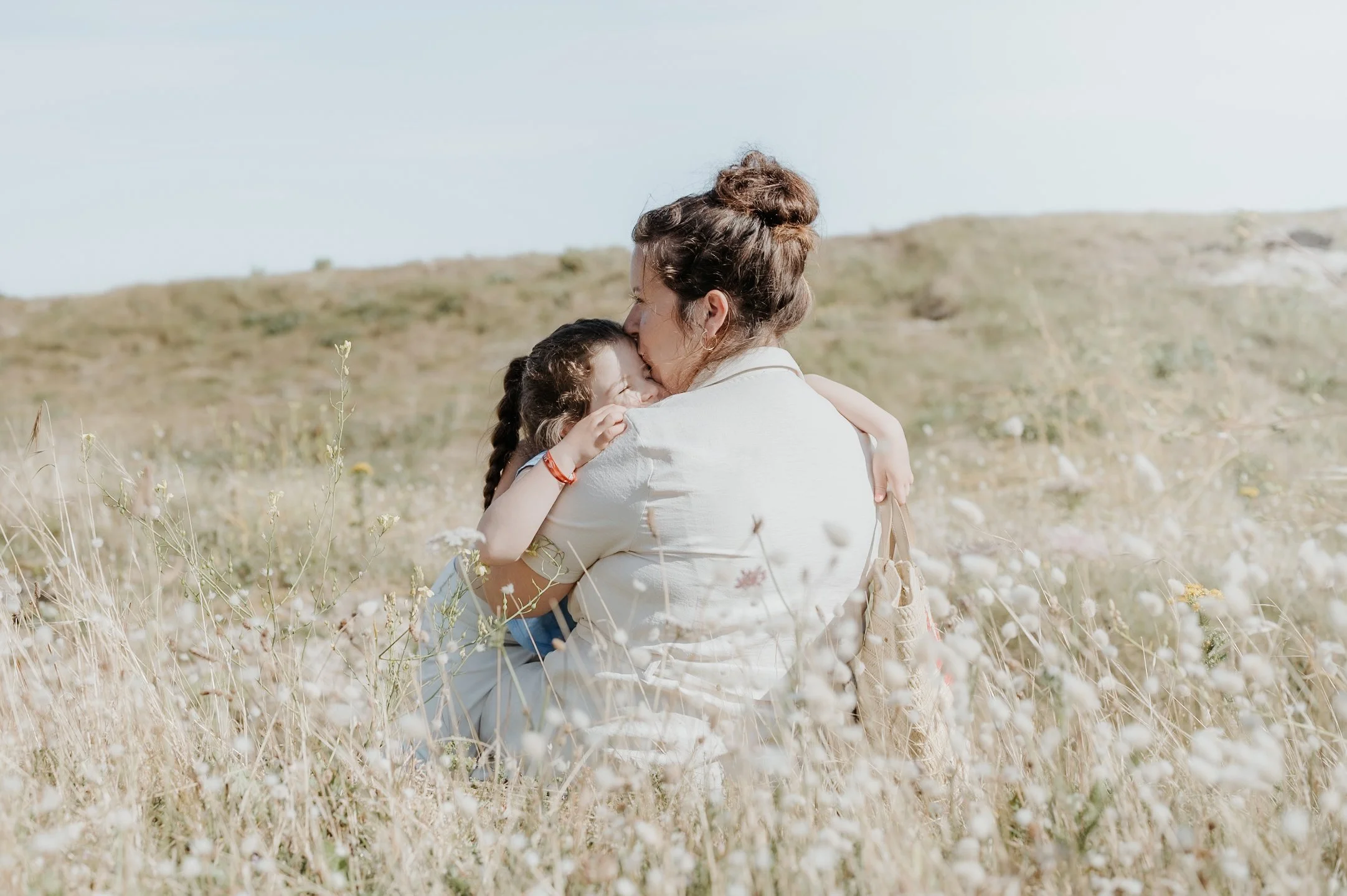 Une femme et une enfant s'embrassent dans un champ de fleurs sauvages.