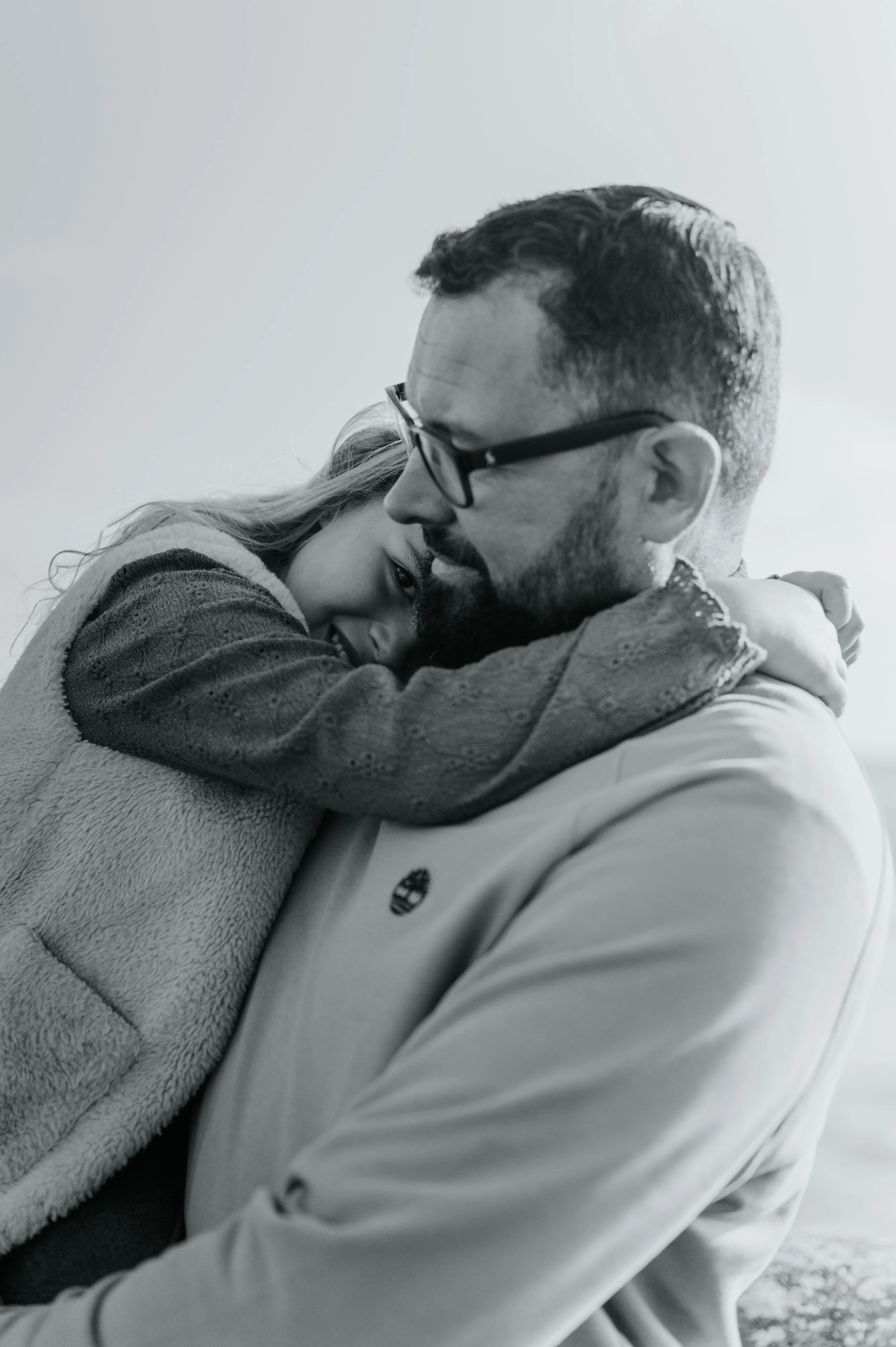 Deux personnes qui s'embrassent, dont une femme et un homme portant des lunettes, dans une ambiance chaleureuse et intime.