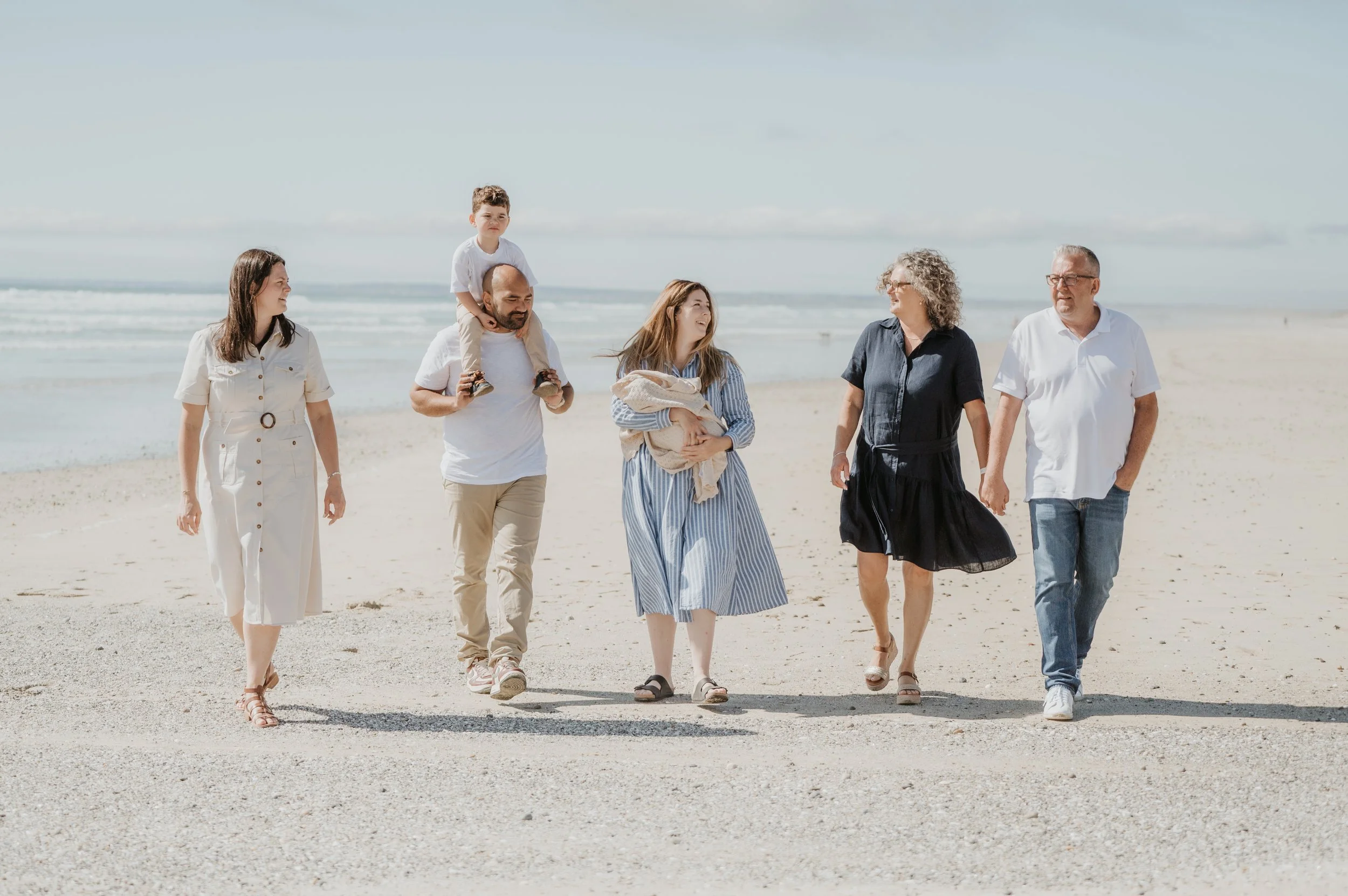 Groupe de personnes marchant sur la plage par une journée ensoleillée.