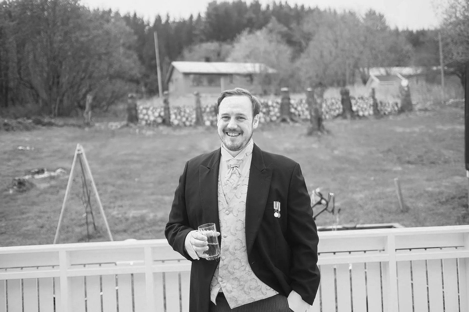 Et bilde av en bryllupsfotograf som heter Sebastian Eriksen. Han er kledd i sort dress og smiler til kamera