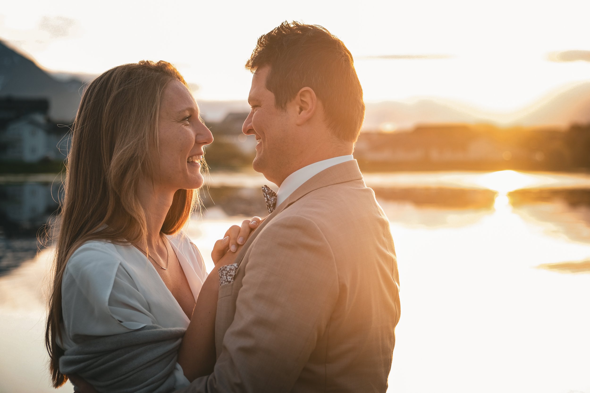 Brudepar i midnattsol i Lofoten. Elopement i Lofoten. Par som holder hverandre og smiler.