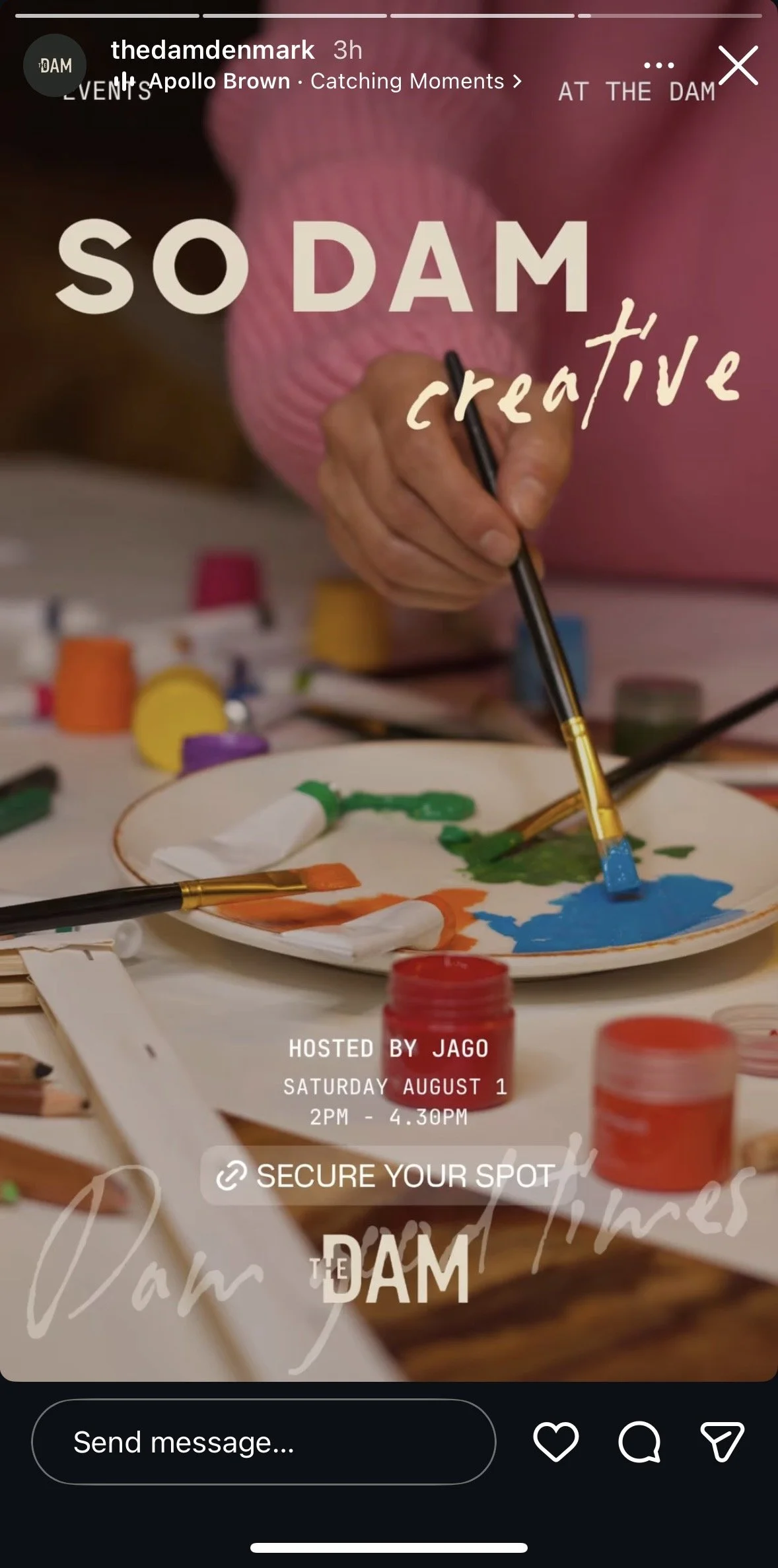 Close-up of an artist's hand with a paintbrush creating colorful abstract art on a plate, surrounded by paint containers, brushes, and art supplies on a table.