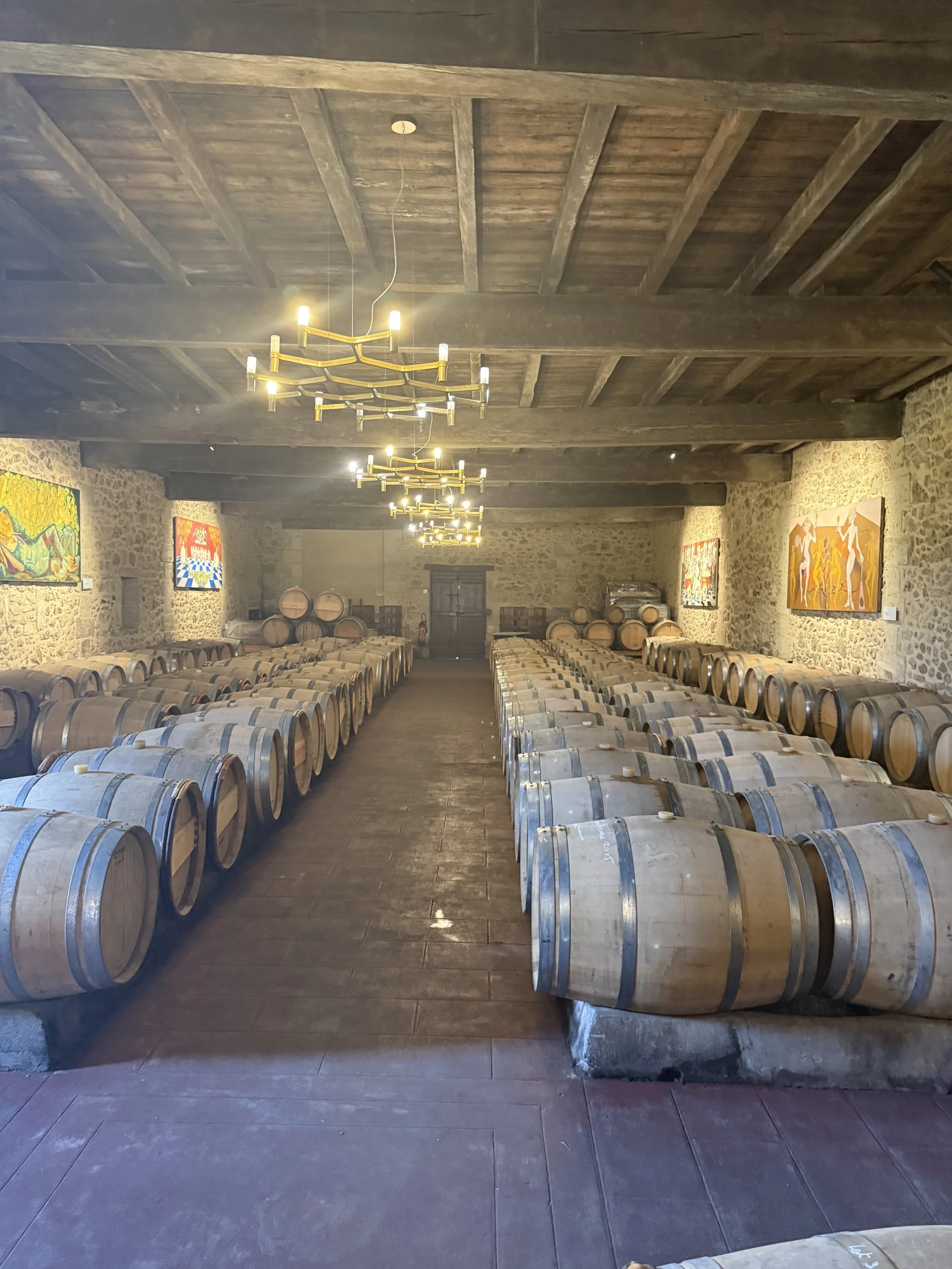 Eine Weinkellerei mit Holzfässern, Steinwänden und modernen Beleuchtungen, die für die Weinlagerung genutzt werden.