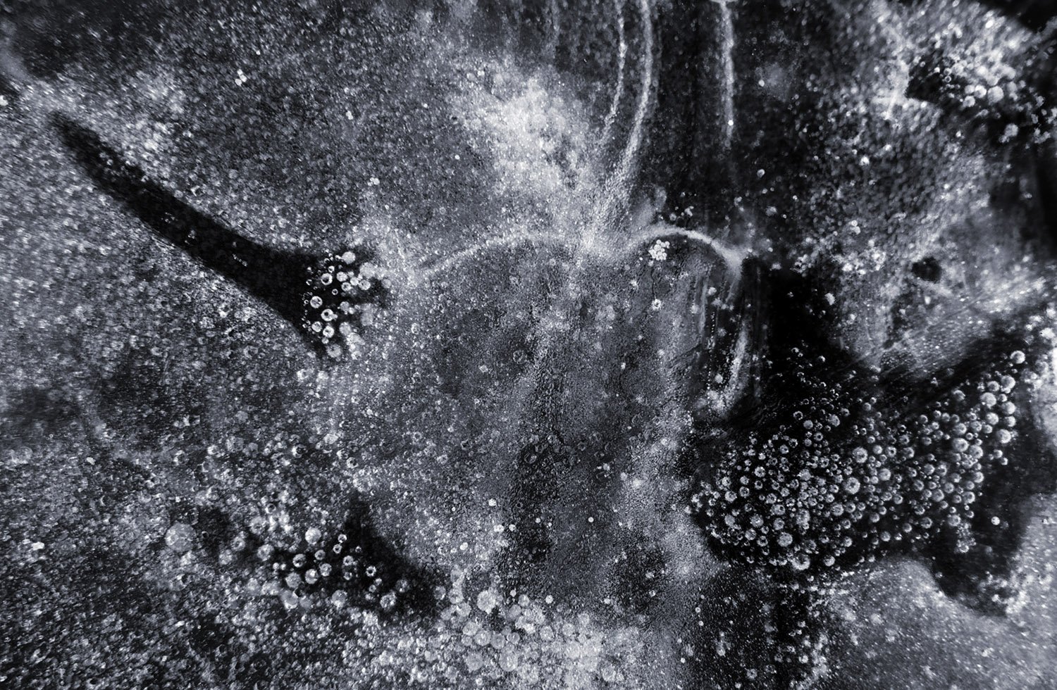 Close-up of dark liquid with white bubbles, possibly carbonated or icy drink.