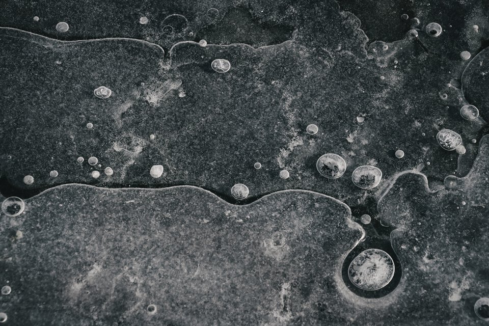 Close-up of frozen bubbles trapped in ice with textured surface