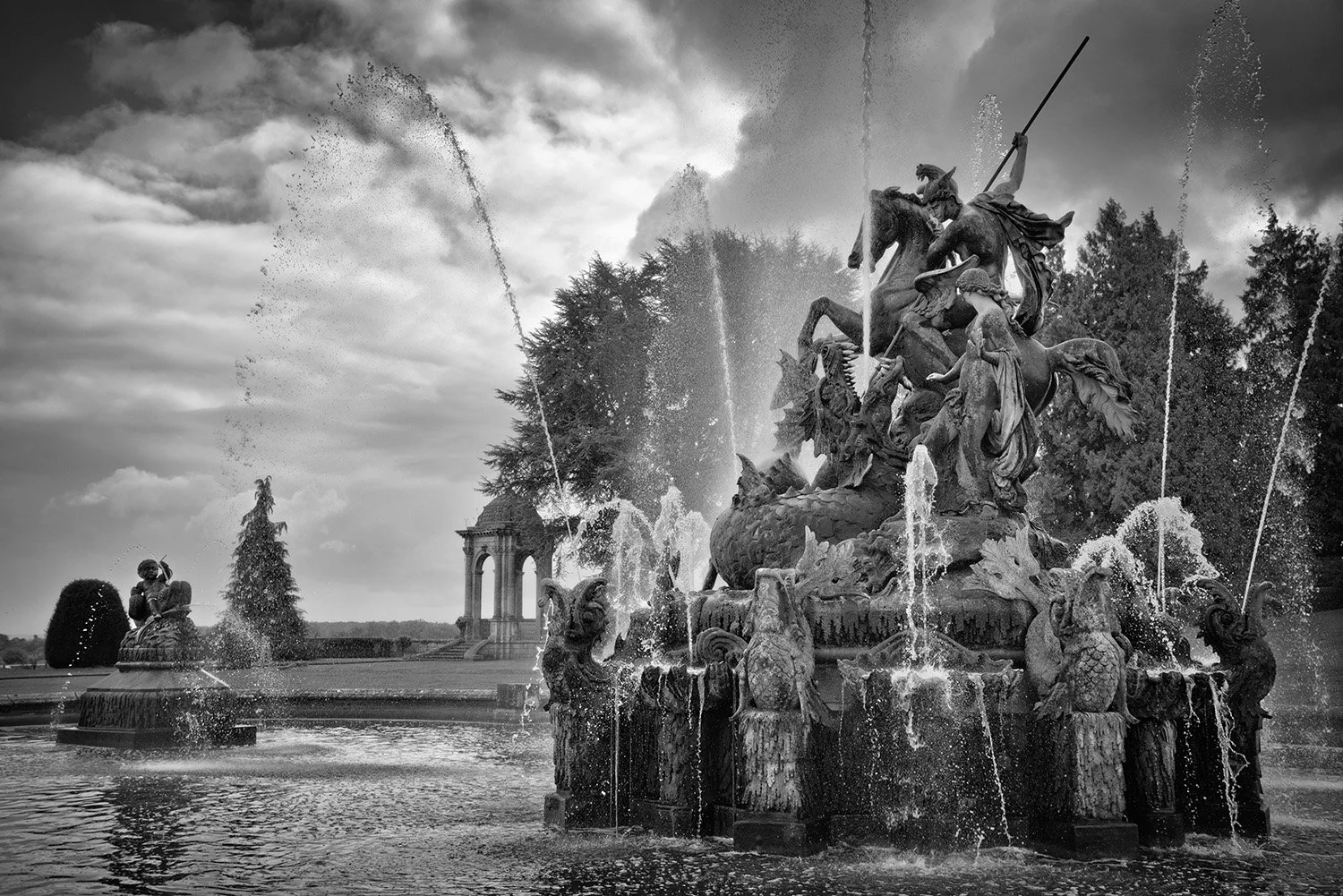 A black and white photo of an ornate fountain with statues of mythological figures Perseus and Andromeda, multiple water fountain jets.