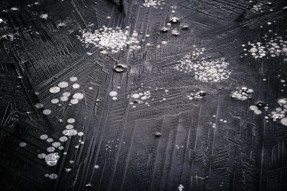 Close-up of a glass surface with water droplets and streaks, possibly from condensation or melting ice.