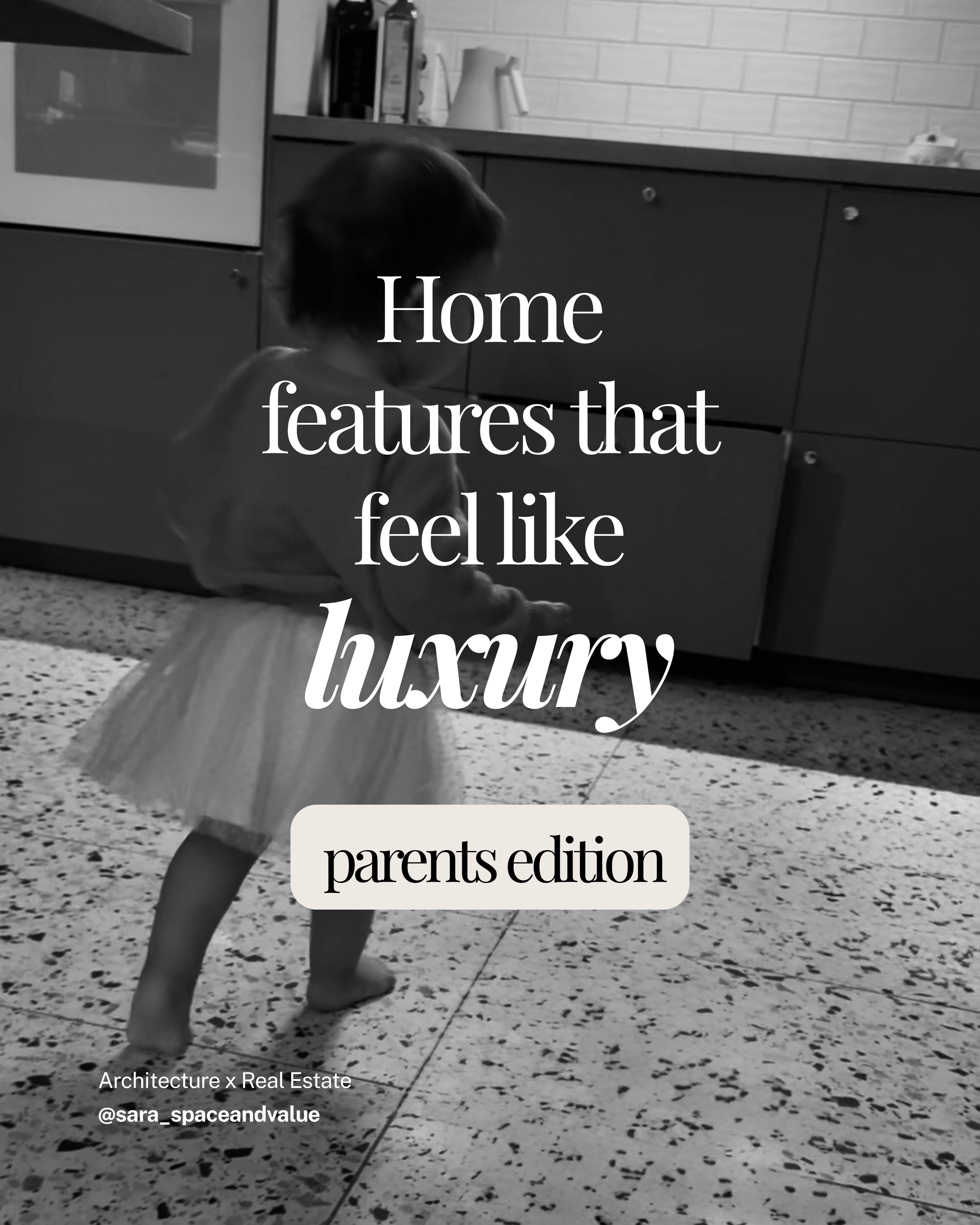 A black and white photo of a child sitting on a speckled tile floor in front of a kitchen cabinet, with the text overlay 'Home features that feel like luxury'. The child's head is slightly bowed, and they are facing away from the camera. The kitchen in the background has a countertop with various objects including a bottle and a pitcher.