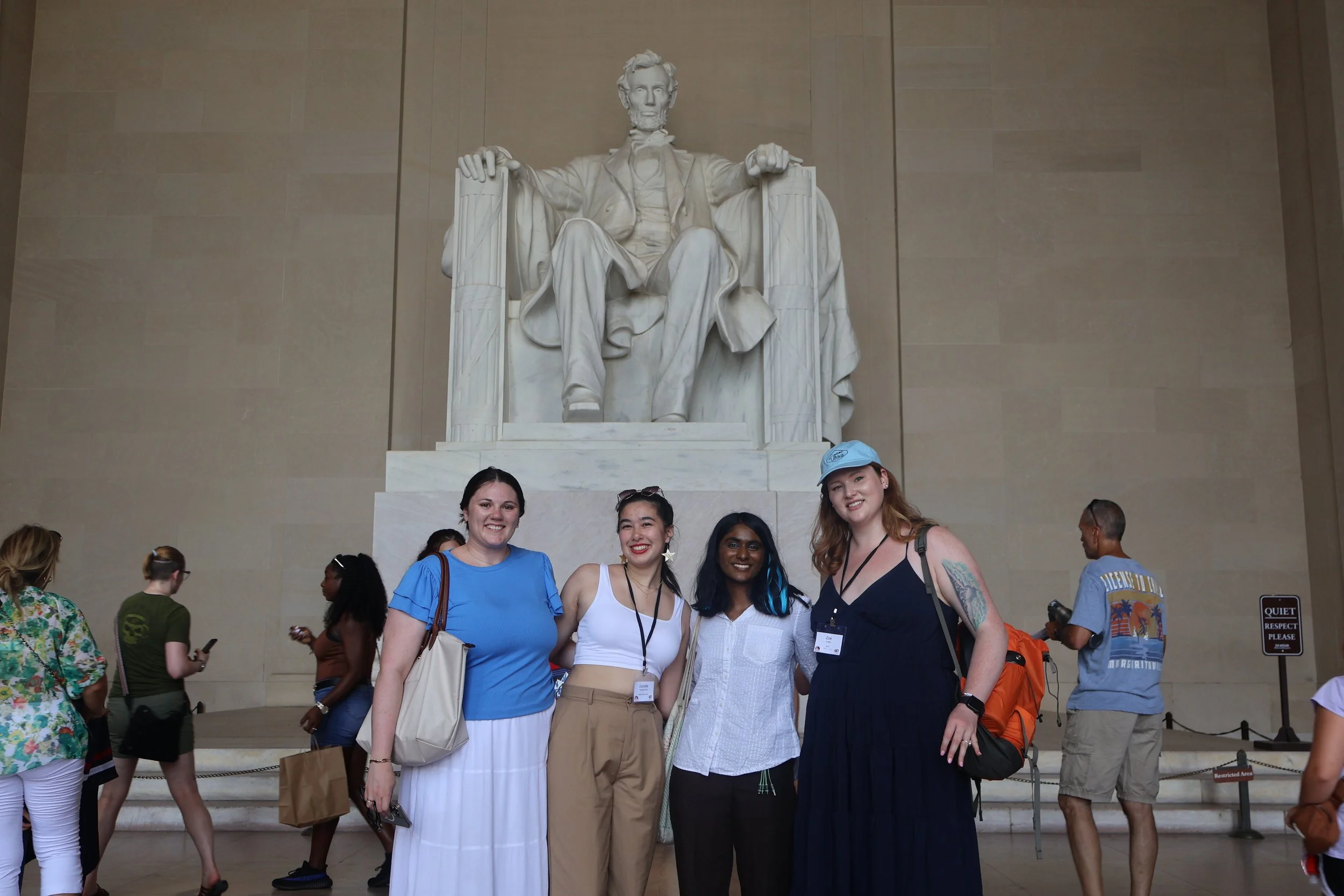 Four women stand in front of the Lincoln Memorial during daytime, smiling and posing for a photo. The large statue of Abraham Lincoln is visible behind them.Walking Tour of Washington D.C., CBYX AA National Reunion, 40th Year Anniversary. 