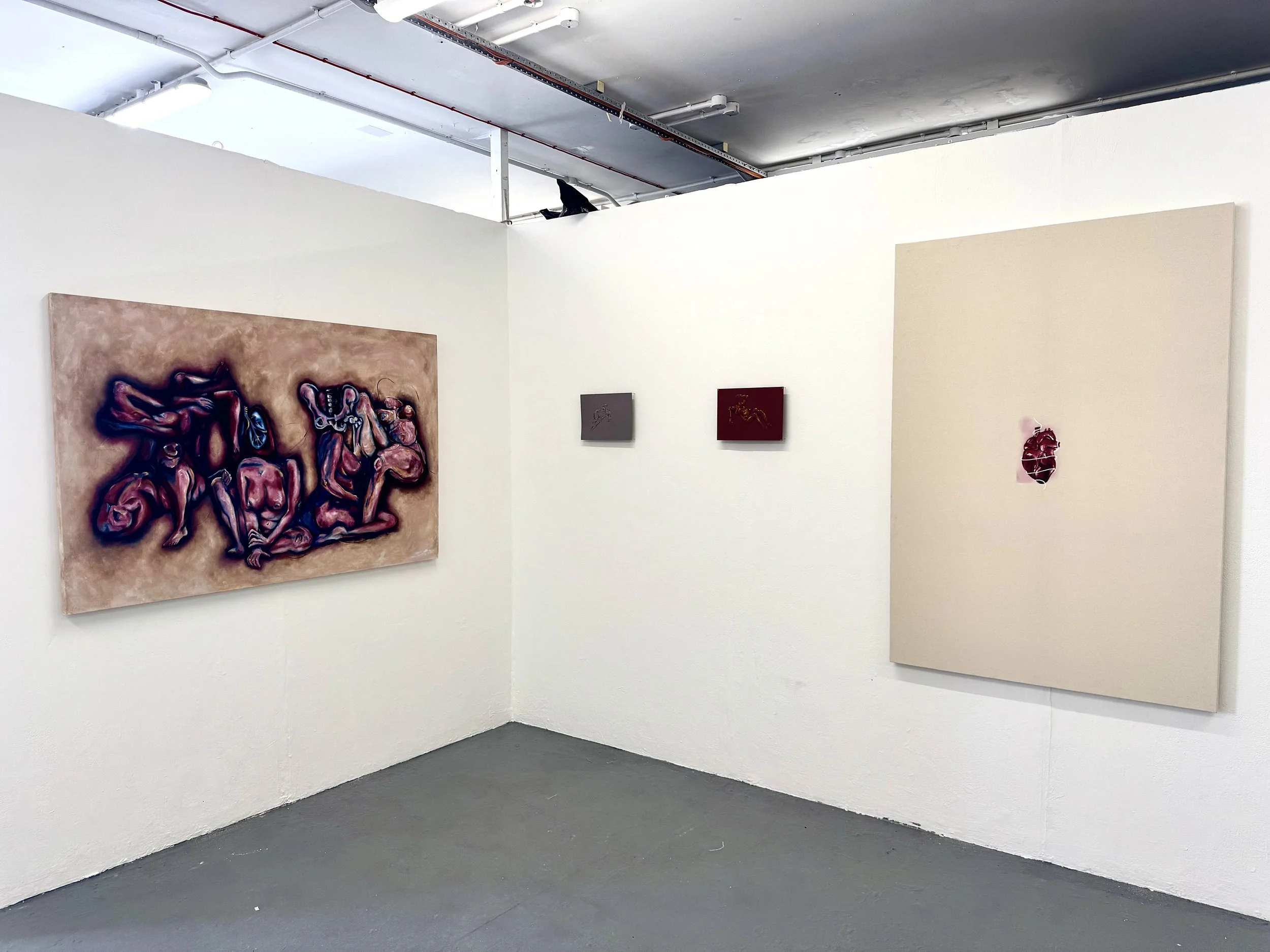 Interior of an art gallery with white walls displaying paintings, including a large, abstract piece with intertwined figures and smaller artworks with minimal designs, under a ceiling with exposed pipes and track lighting.
