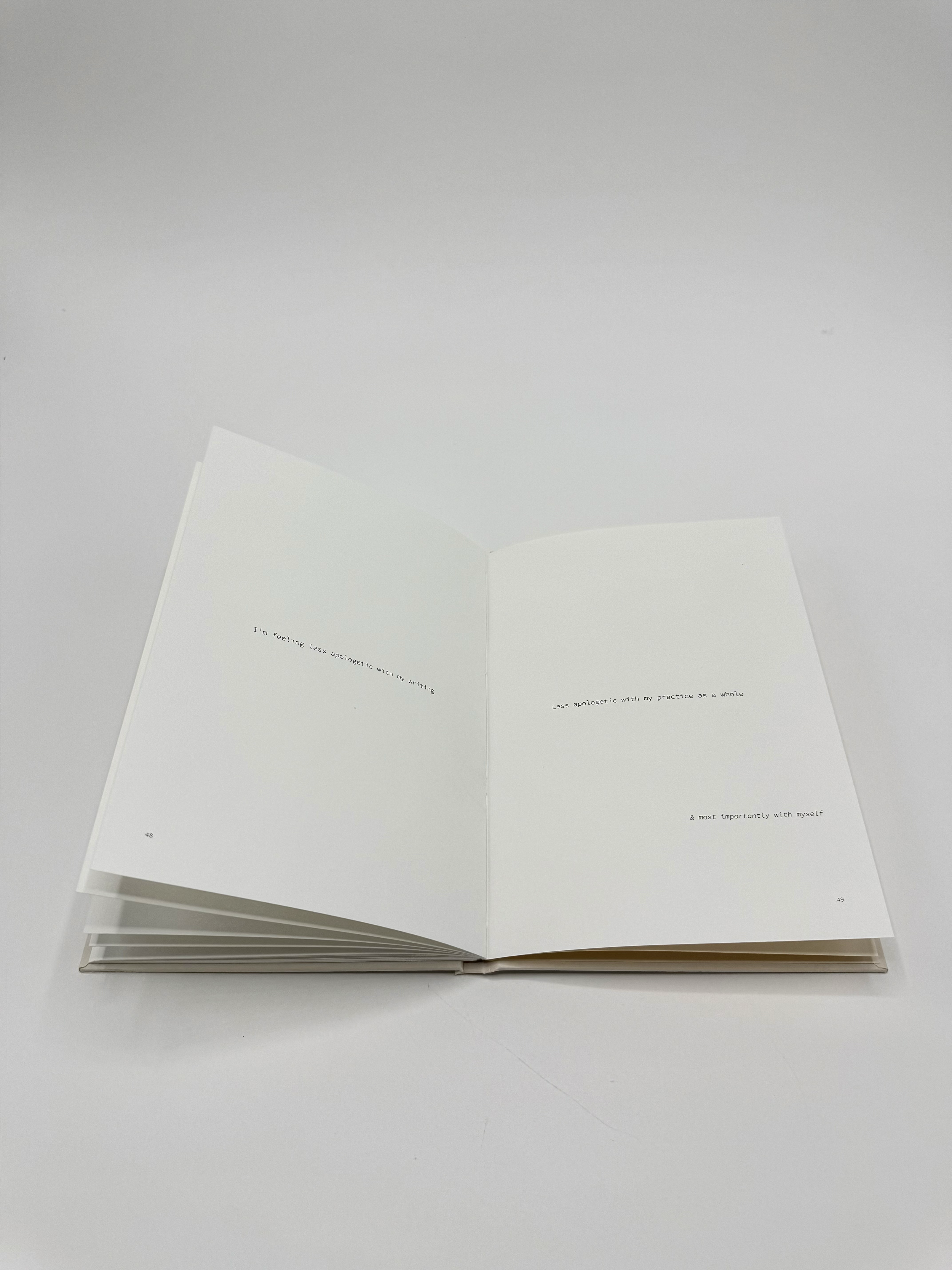 Open white book with small, black serif text on both pages, resting on a plain white surface.