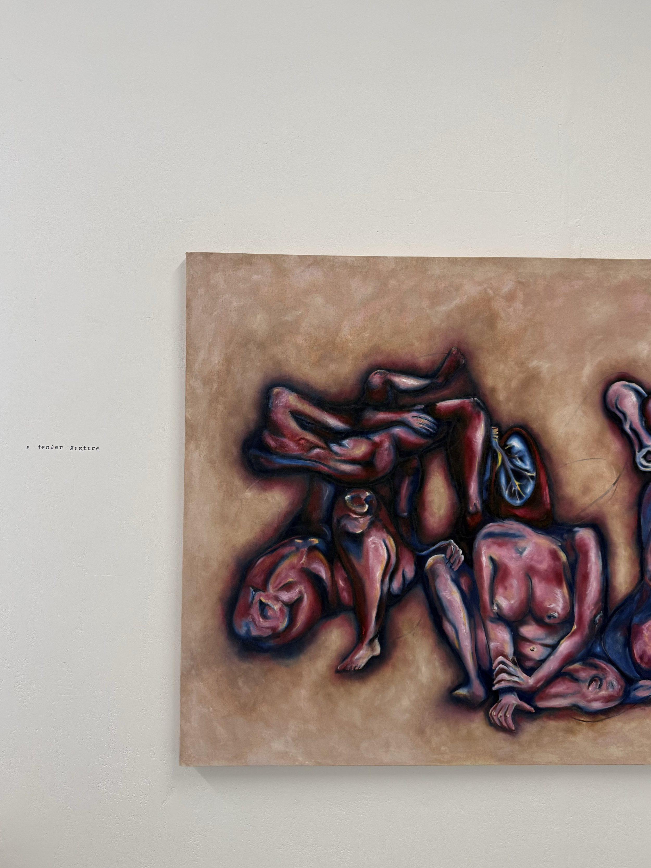 A painting of several intertwined human figures in an abstract style with vivid colors, placed against a neutral background in an art gallery.