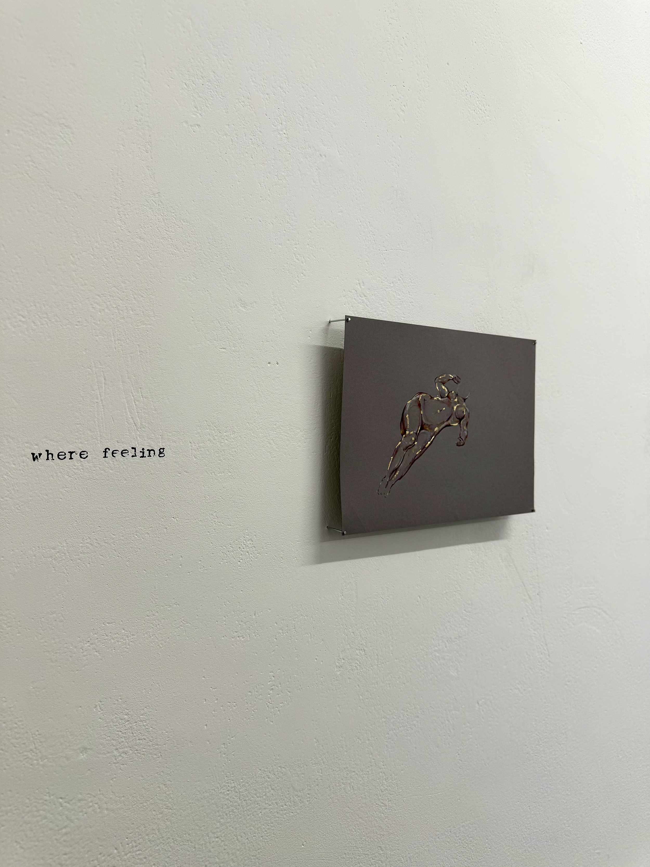 A black poster featuring a gold outline of a running horse, mounted on a white wall with a small portion of the text 'where feeling' handwritten at the bottom left.