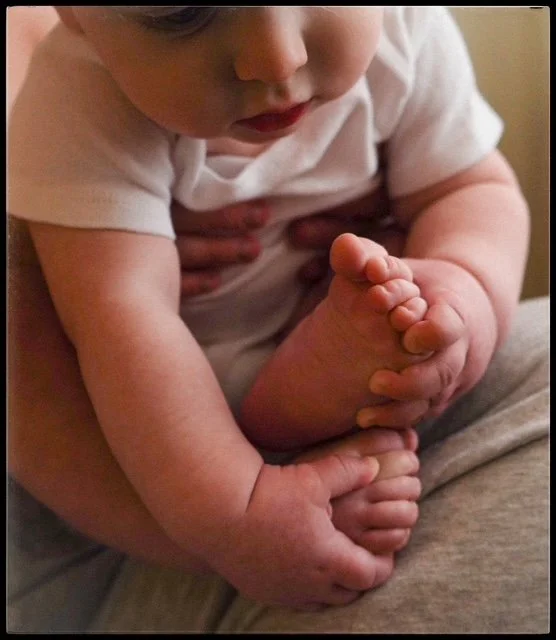 Close-up of a child's hand holding their foot.