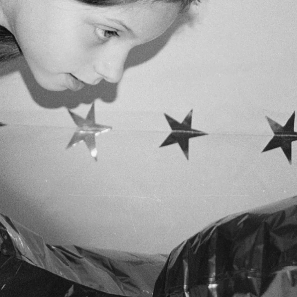 Close-up of a child's face looking down at a table with star-shaped foil decorations.