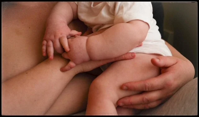 A close-up of a child holding an adult's hand.