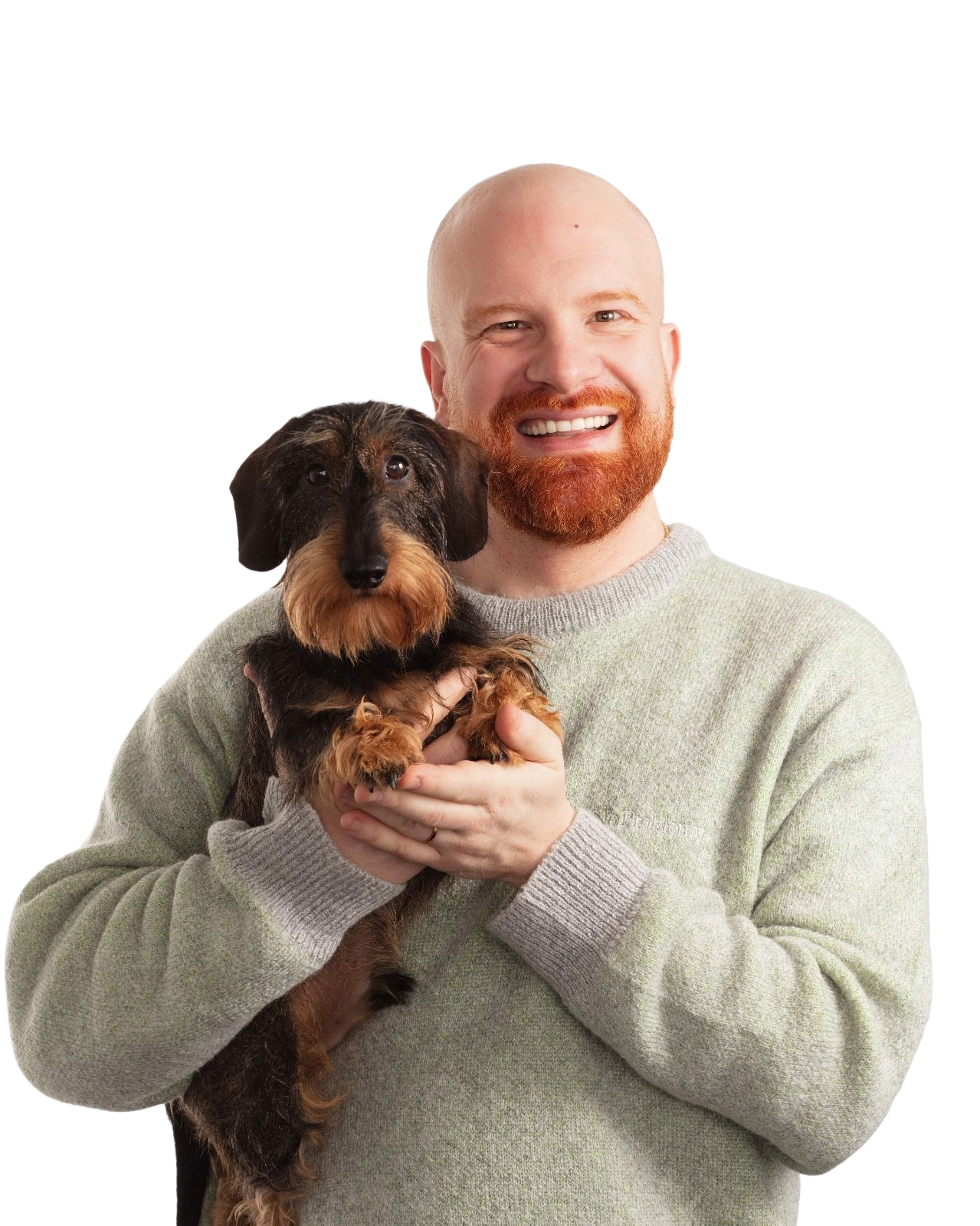 A smiling man with a red beard wearing a gray sweater is holding a small black and brown dachshund dog. The background is plain white.