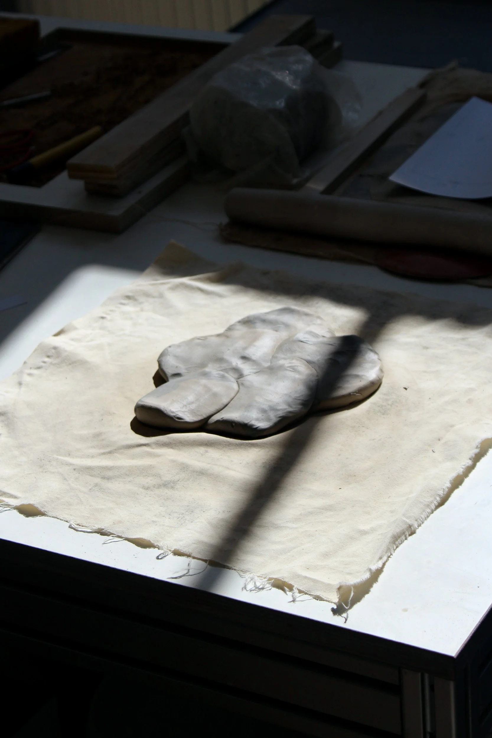 Ceramic stones and white fabric in natural light at Vuur Collective studio, Amsterdam. Detail photography by Isabel Hachmann-Peralt.