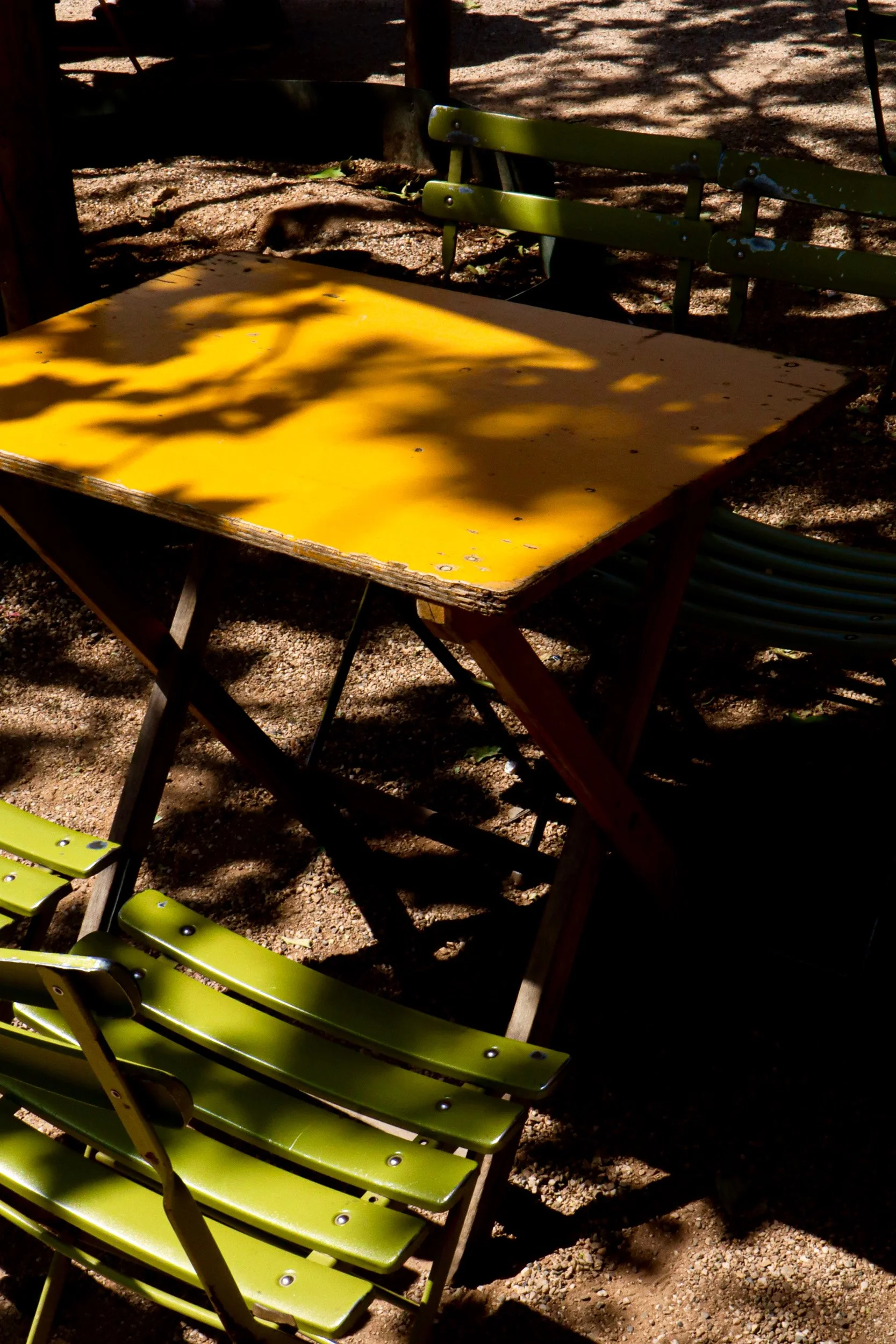 Yellow table and green chairs in sunlight, Amsterdam. Colour street photography by Isabel Hachmann-Peralt.